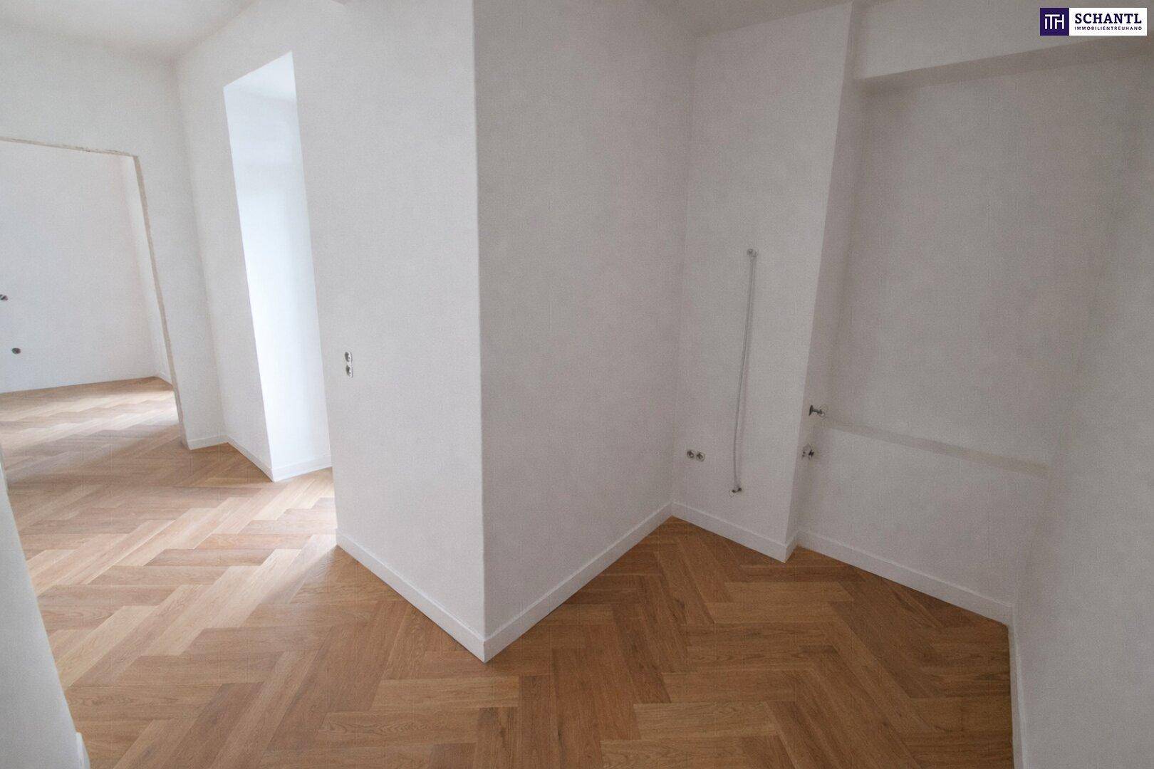 Leerer Raum mit Fischgrätparkett und Wandanschlüssen, möglicherweise für eine Küche oder Waschküche.