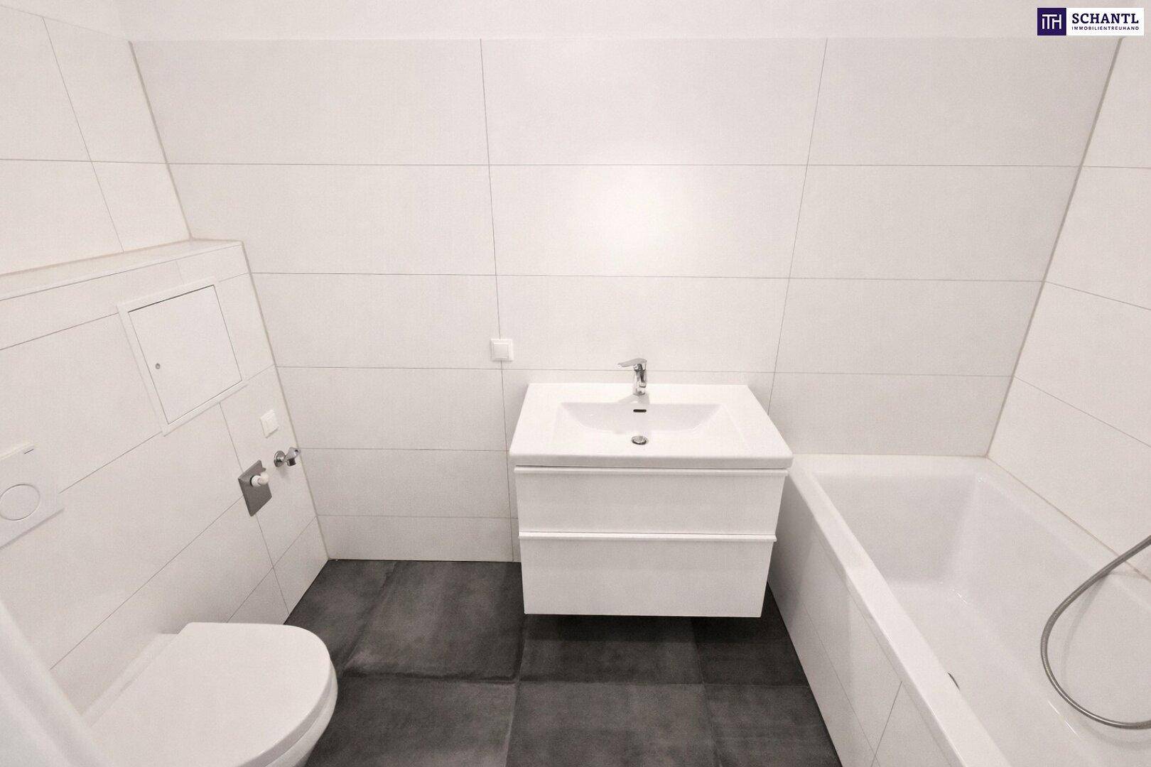 Modernes Badezimmer mit Waschtisch, Badewanne und Toilette, hell gefliest.