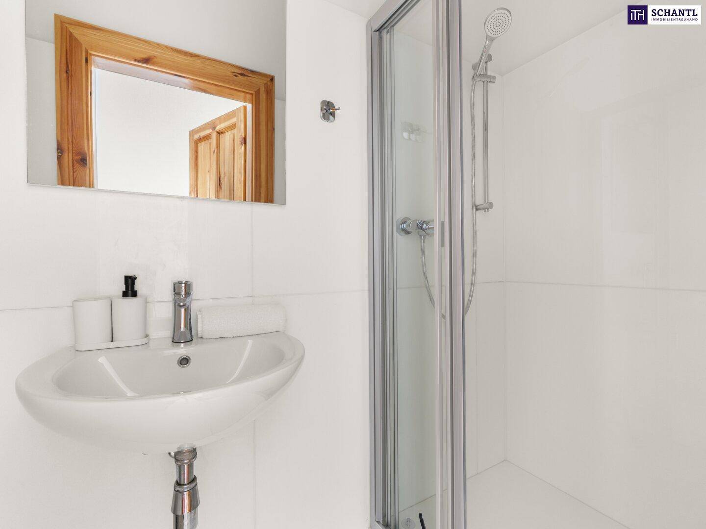 Modernes Badezimmer mit Duschkabine, weißem Waschbecken und Spiegel.
