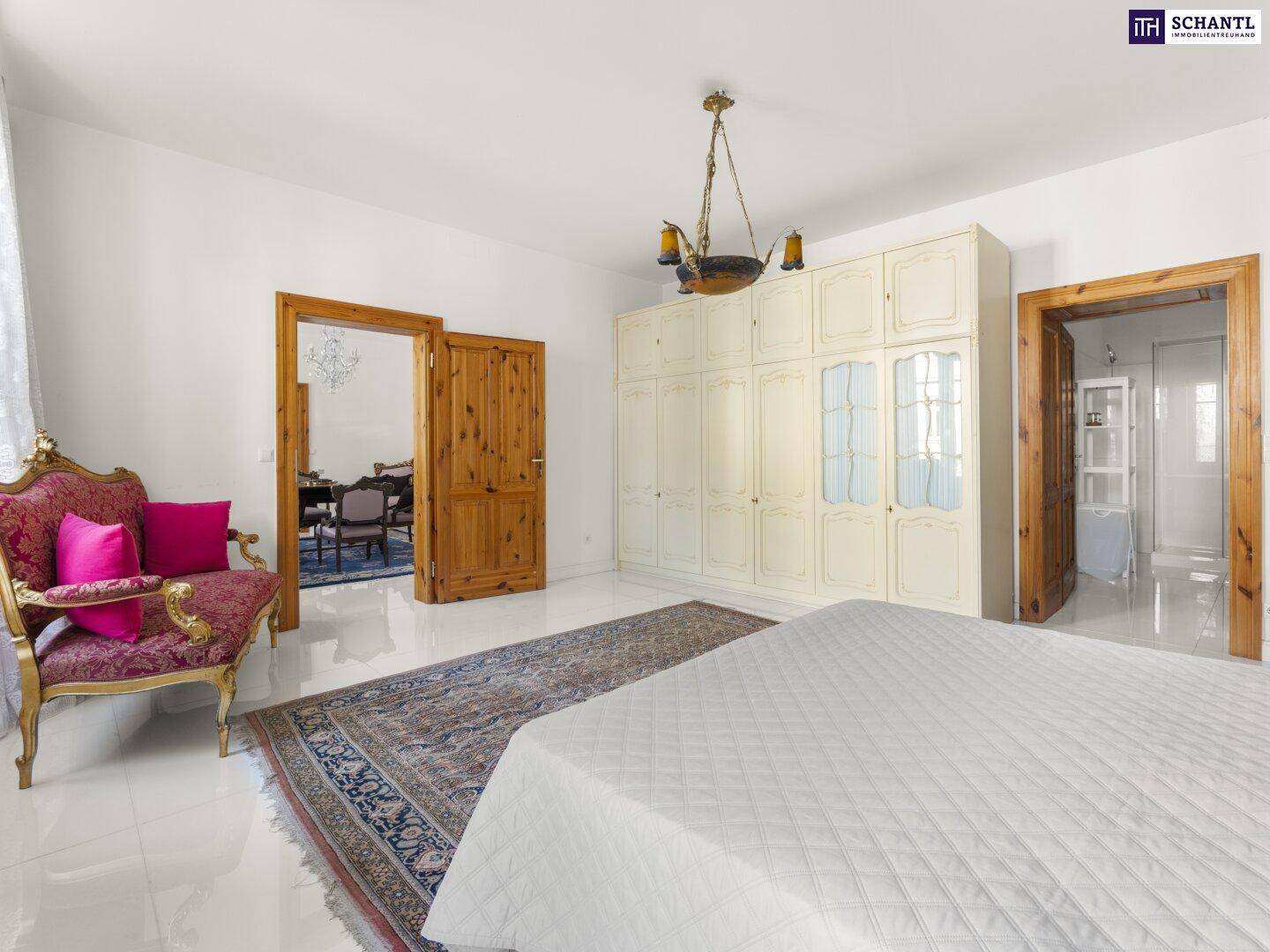 Geräumiges Schlafzimmer mit großen Fenstern, Einbauschränken und einem orientalischen Teppich.