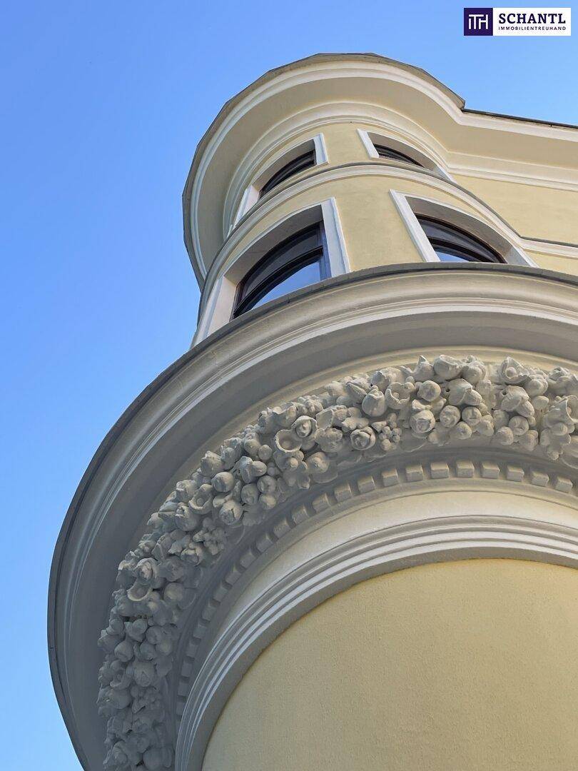 Detailansicht der historischen Fassade mit dekorativen Stuckelementen und runden Fenstern.