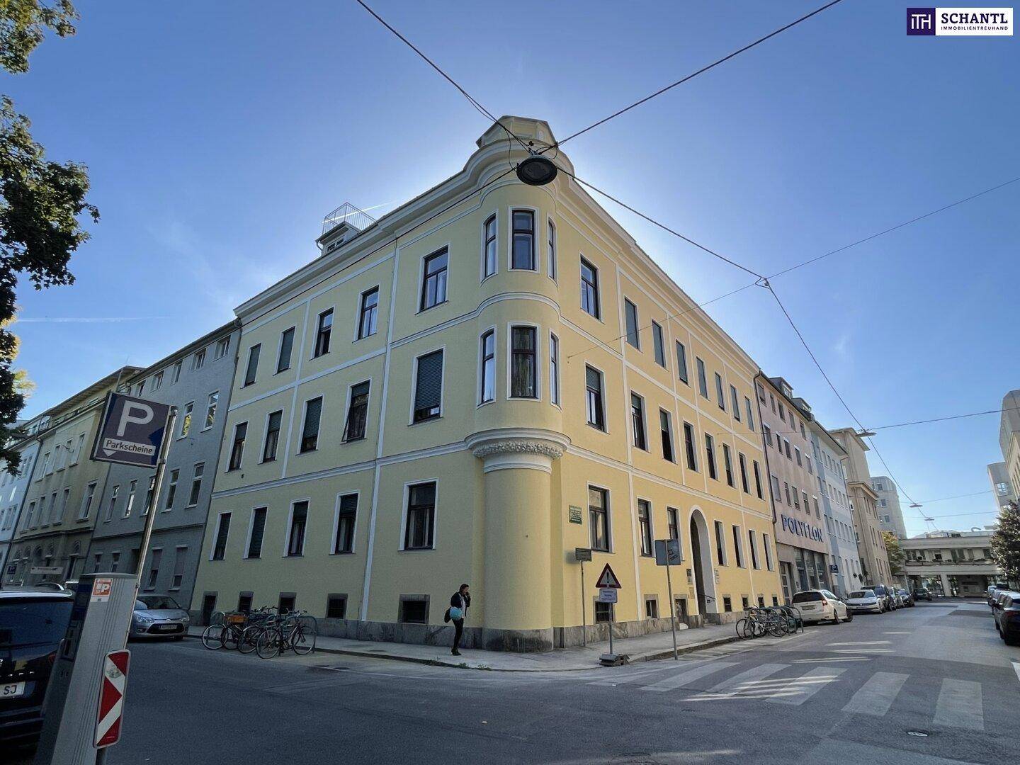Historisches Eckgebäude mit gelber Fassade und vielen Fenstern an einer städtischen Straße.