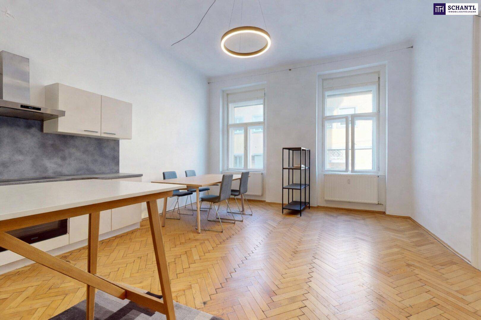 Geräumiger Wohn-Essbereich mit integrierter Küchenzeile, Parkettboden und großen Fenstern.
