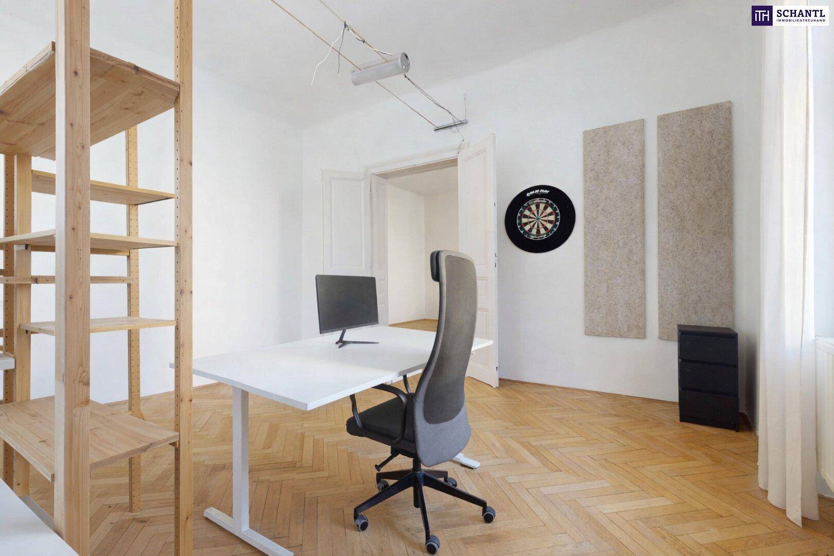 Moderner Arbeitsplatz in einem hellen Raum mit Parkettboden und dekorativer Dartscheibe.