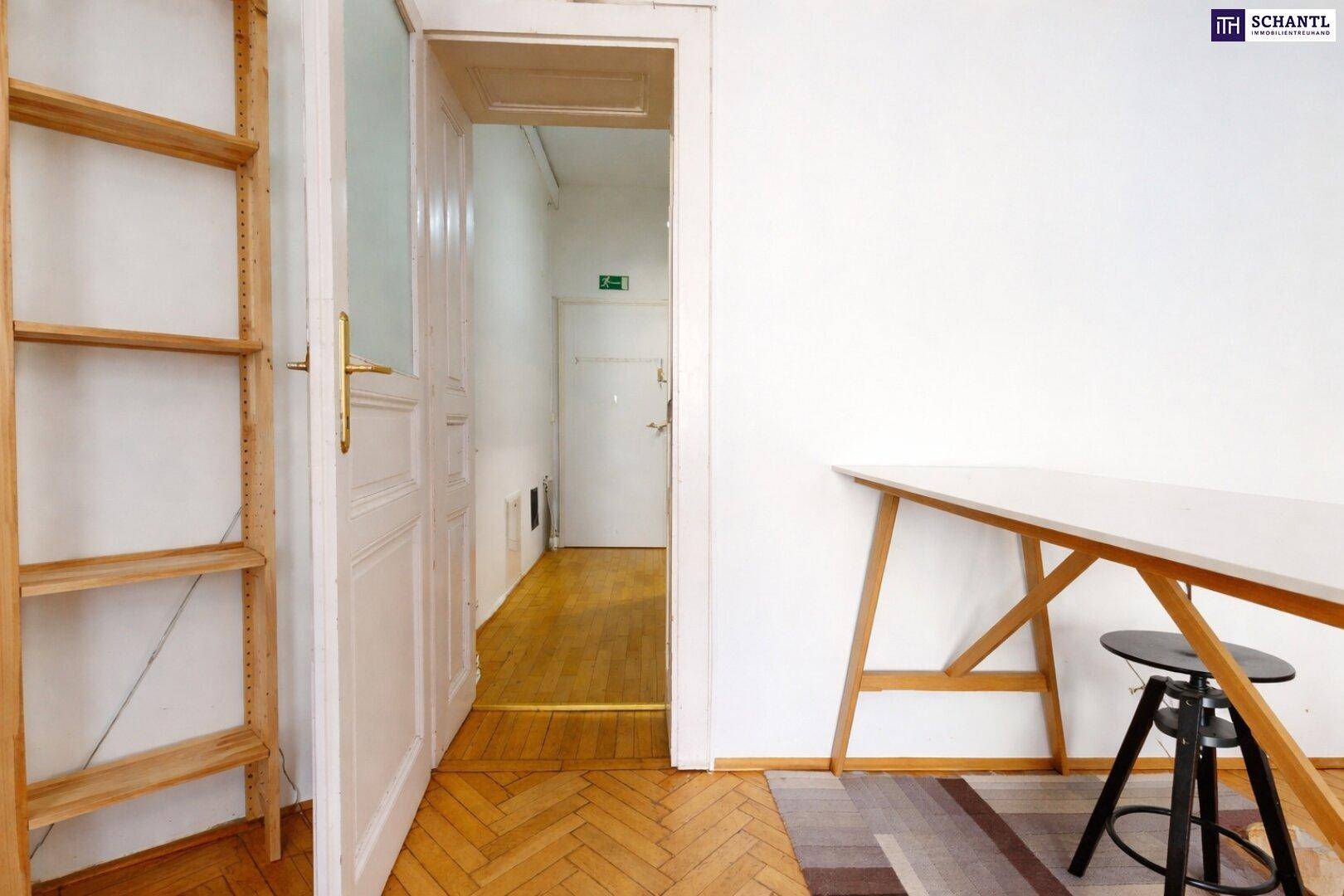 Blick vom Arbeitsbereich in einen Flur mit Holzboden und klassischen Flügeltüren.