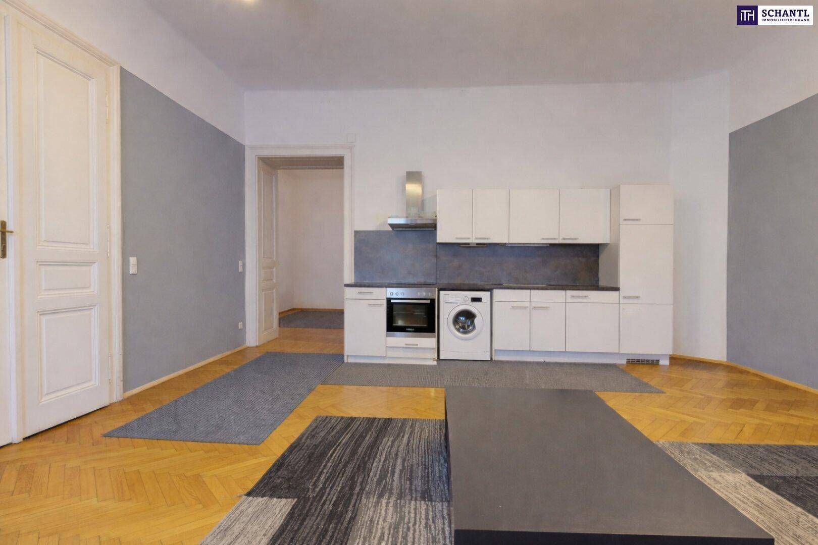 Kleine, funktionale Küche mit weißen Schränken, Backofen und Waschmaschine in einem offenen Raum.