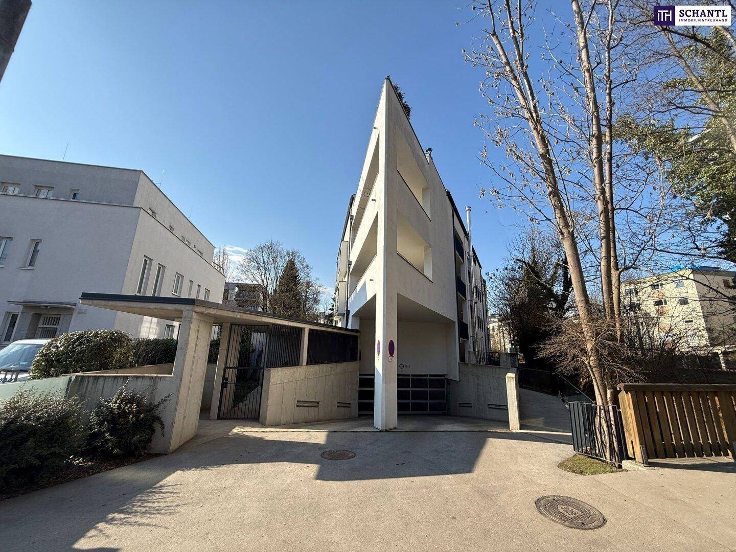 Zeitgenössisches Gebäude mit scharfen Linien und Zugang zur Tiefgarage, umgeben von Bäumen und Vegetation.