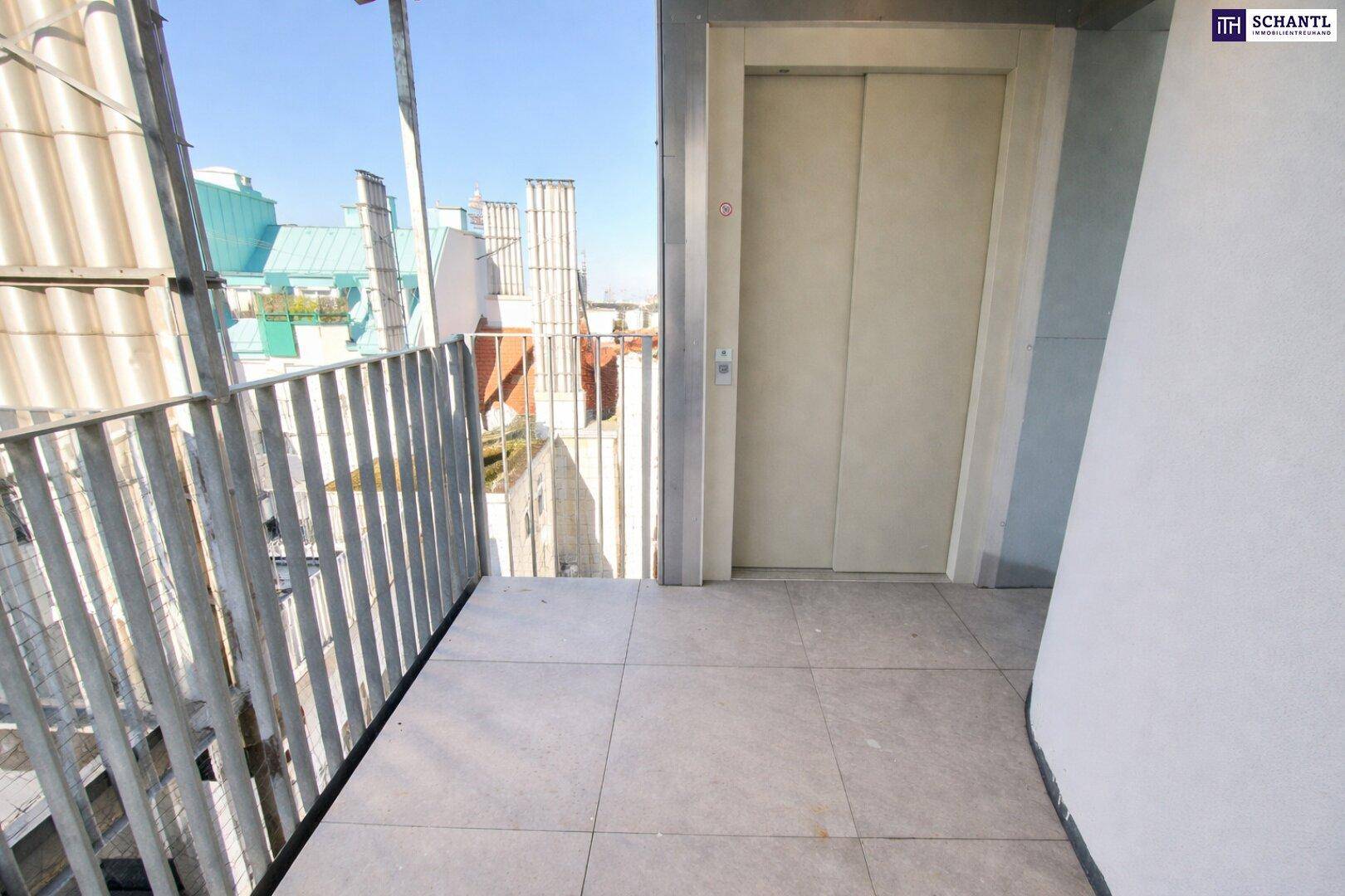 Außenaufzug auf einer Dachterrasse mit Fliesenboden und Blick auf die umliegenden Gebäude.