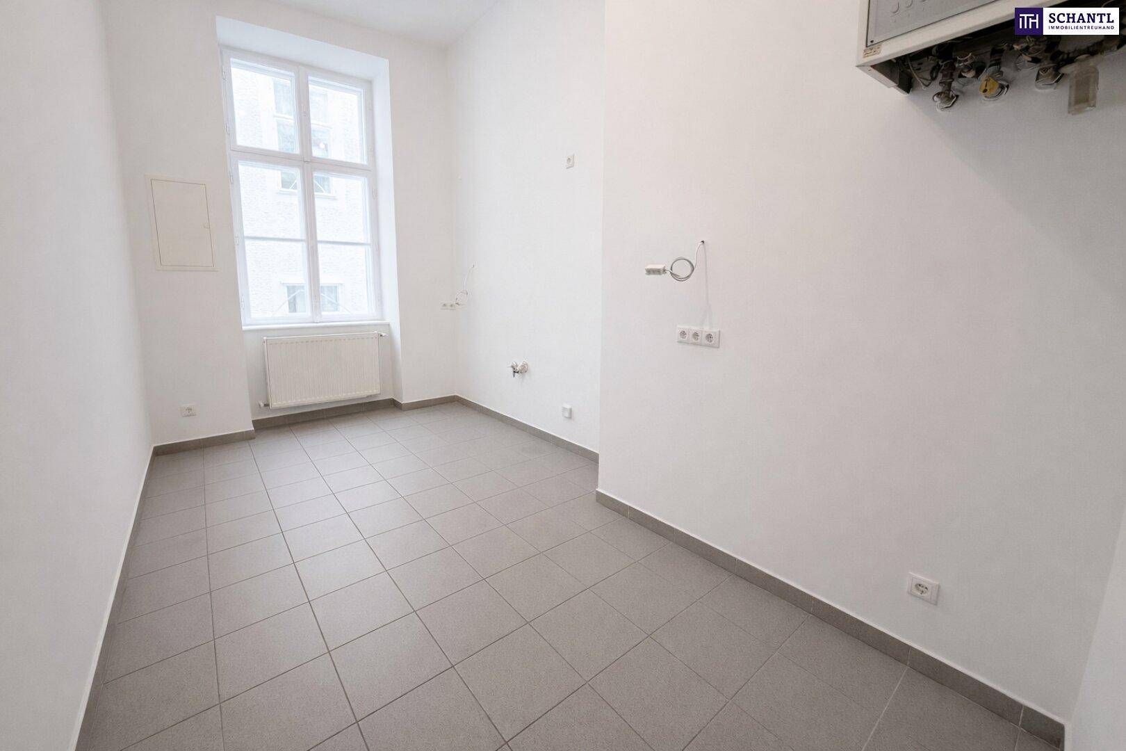 Leerer Küchenraum mit Fliesenboden und Anschlüssen für eine zukünftige, individuelle Einbauküche.