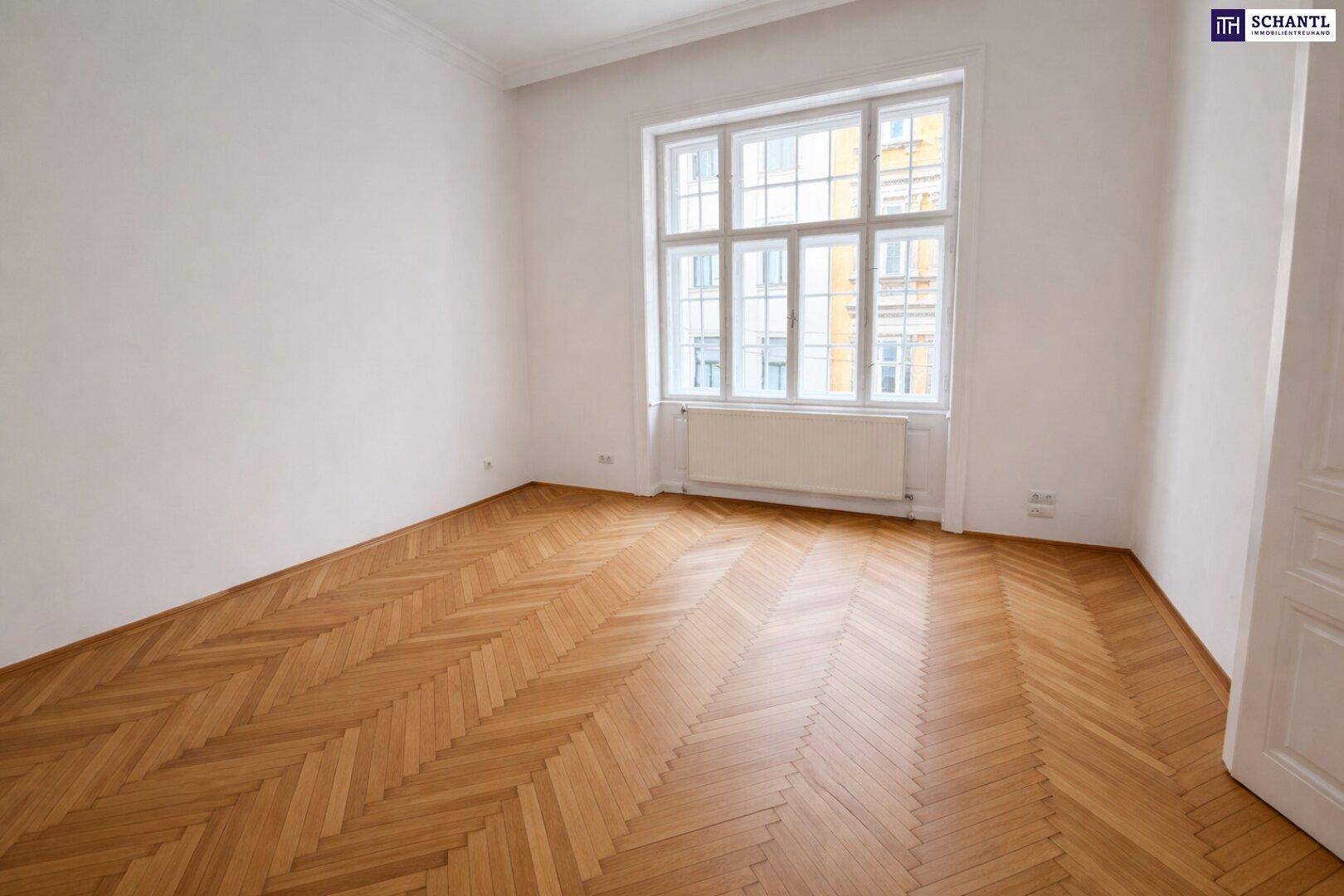 Leeres Schlafzimmer mit Fischgrätparkett und einem großen Fenster, bereit zur individuellen Einrichtung.