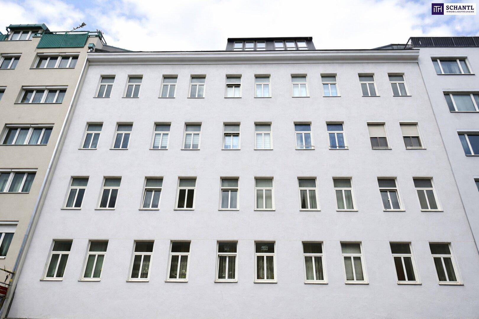 Moderne Gebäudefassade mit zahlreichen Fenstern und weißem Putz.