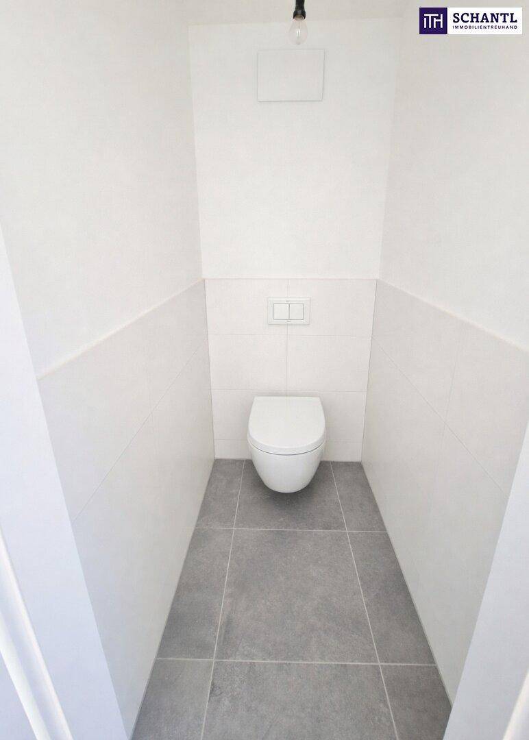 Modernes Gäste-WC mit wandhängender Toilette und grauen Bodenfliesen in neuwertigem Zustand.