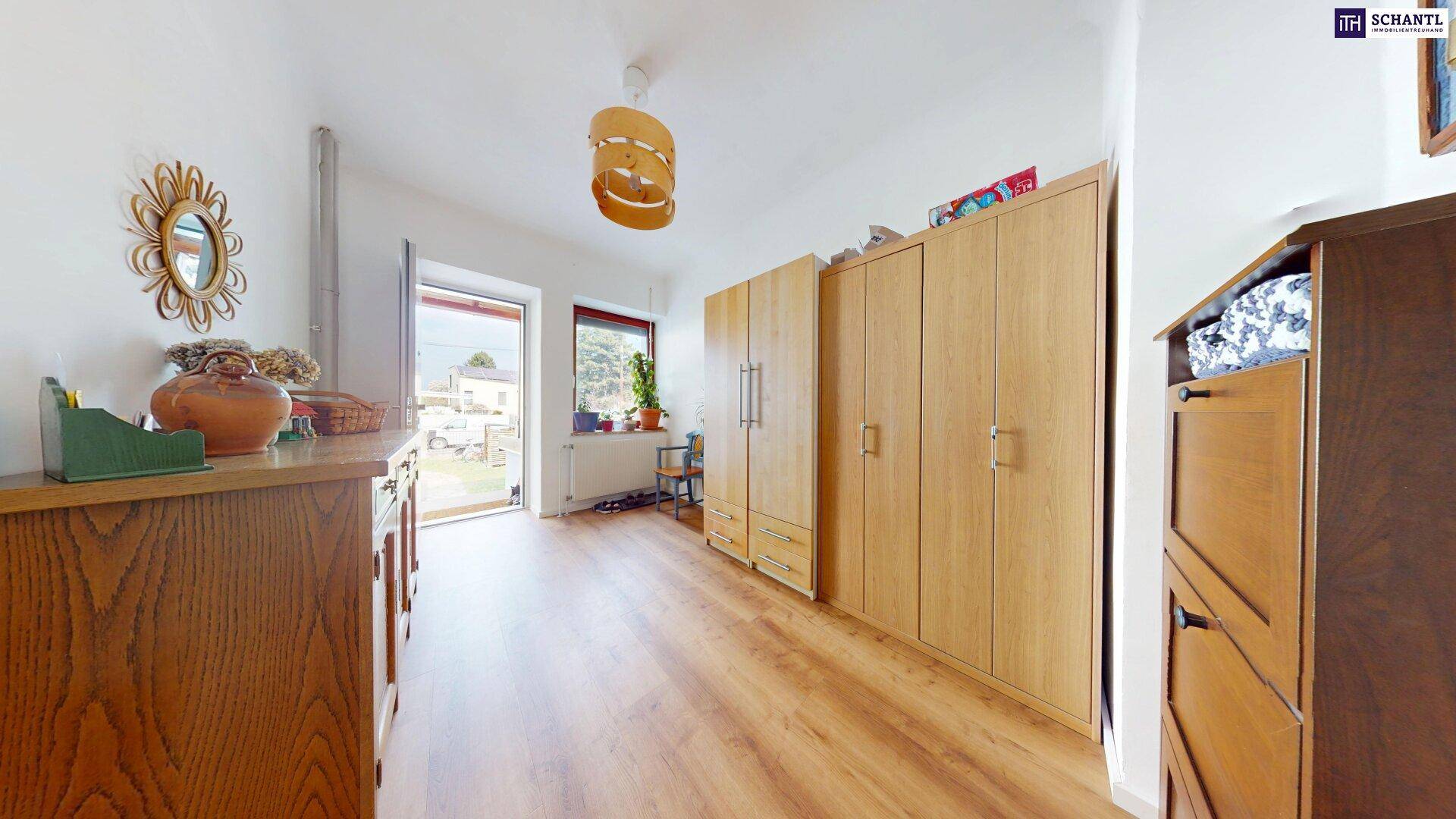 Geräumiger Flur mit Holzboden, Einbauschränken und Zugang zum Außenbereich.