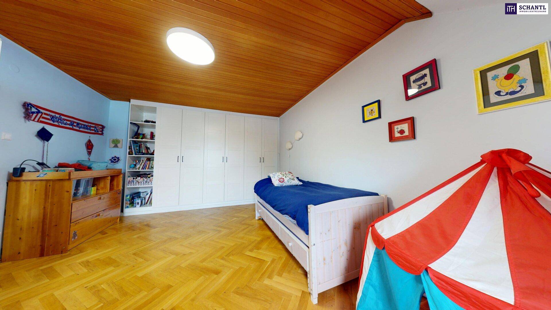 Kinderzimmer mit Holzboden, Einbauschränken und Holzdecke unter Dachschräge.