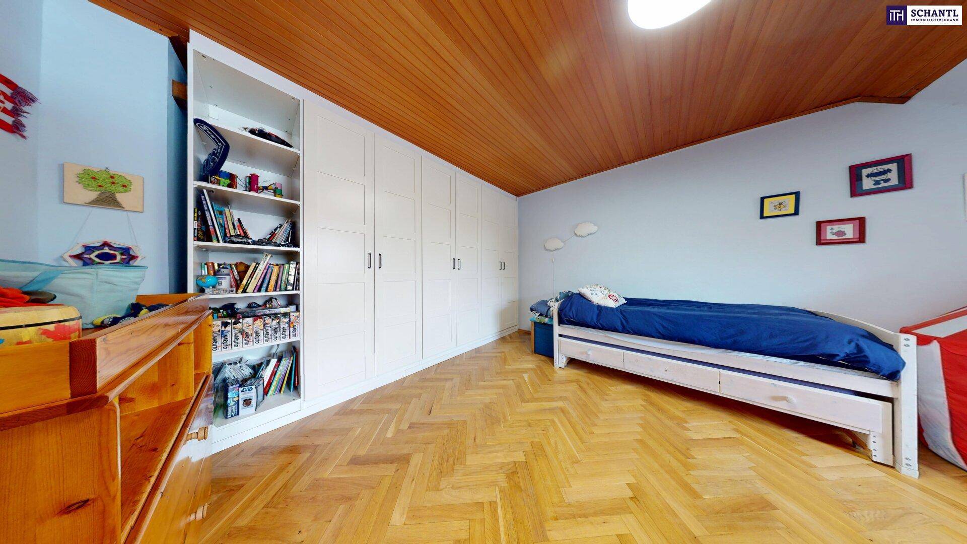 Kinderzimmer mit Holzboden, Einbauschränken und Holzdecke unter Dachschräge.