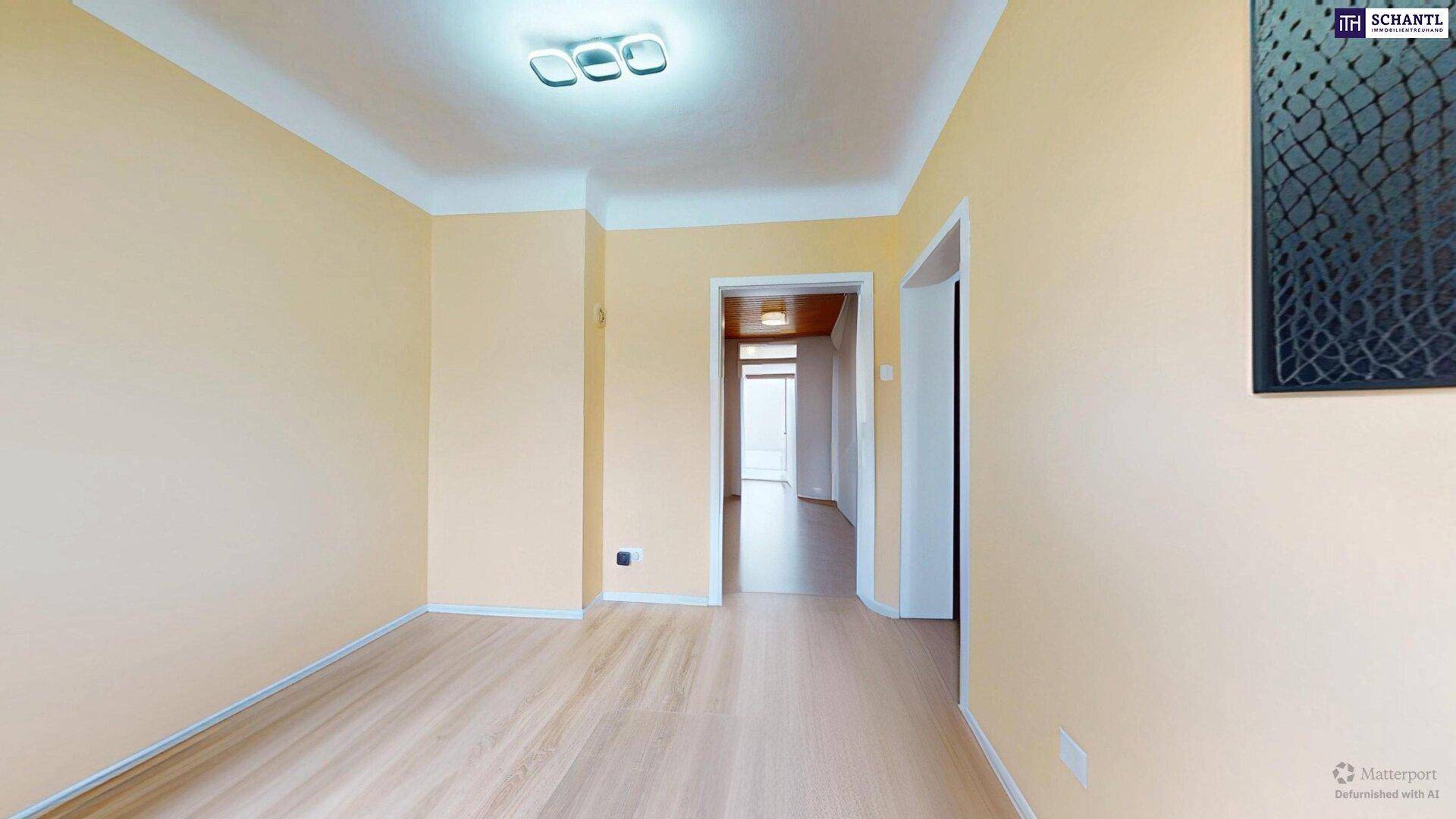 Heller Raum mit beigen Wänden und Holzboden, bereit für Einrichtung.