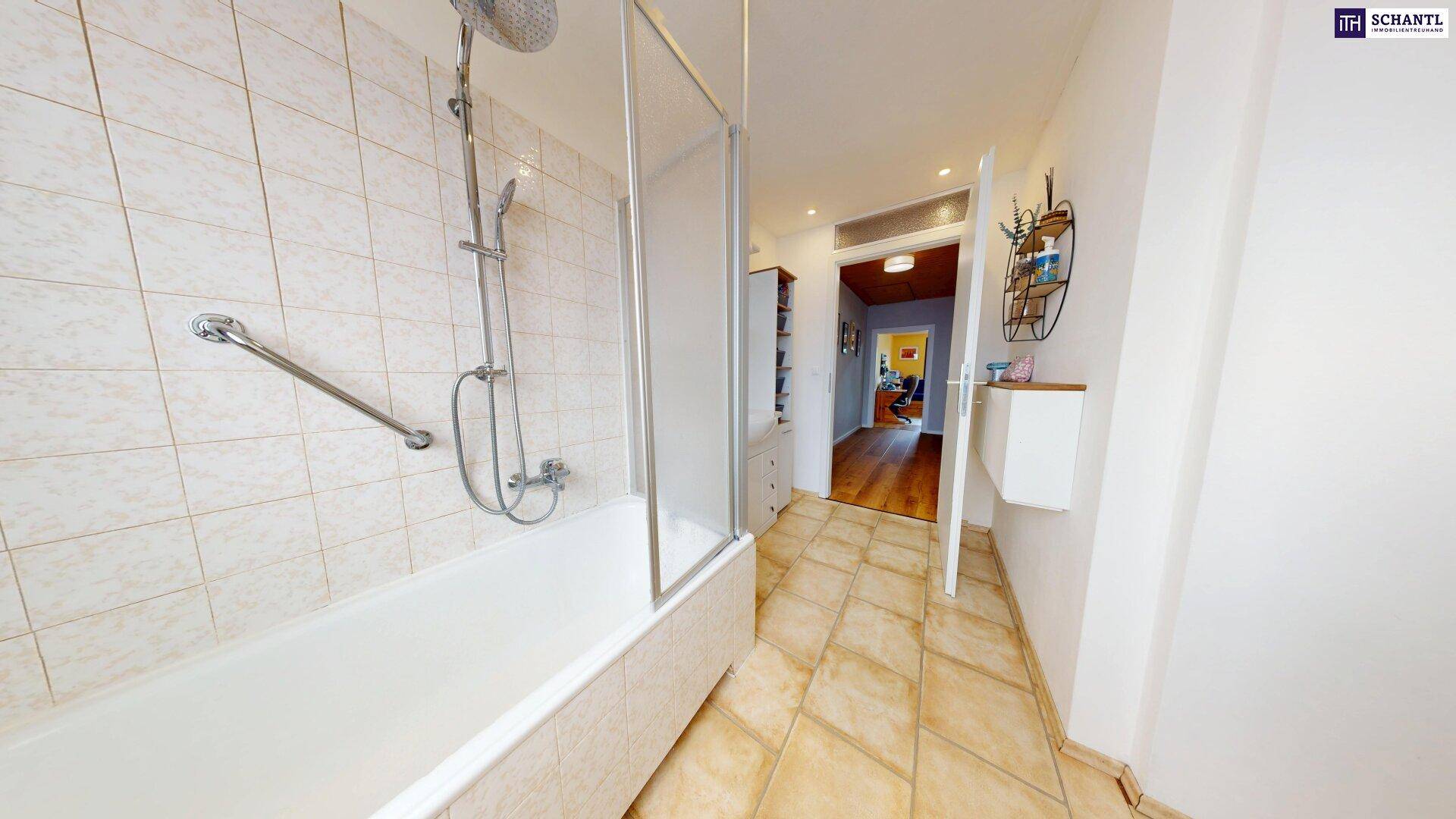 Badezimmer mit Badewanne, Duschvorrichtung und beigen Fliesen.
