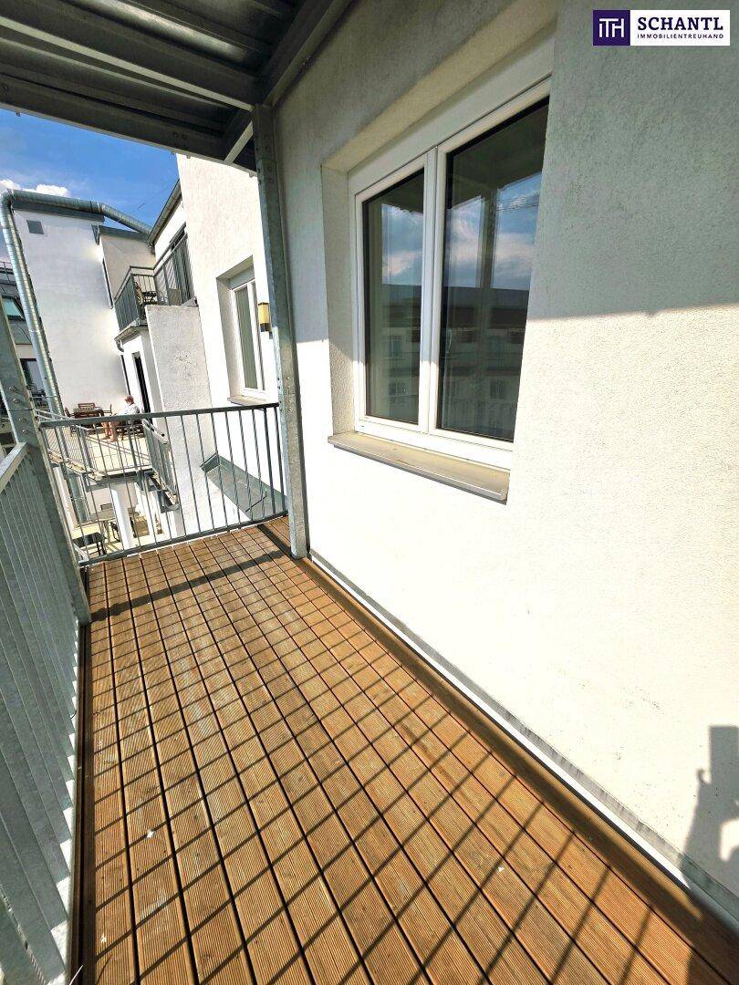 Kleiner Balkon mit Holzdielen und Blick auf benachbarte Balkone.