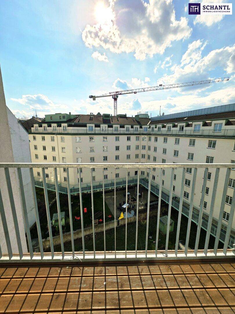 Geräumiger Balkon mit Holzboden und sonnigem Blick auf den Innenhof.