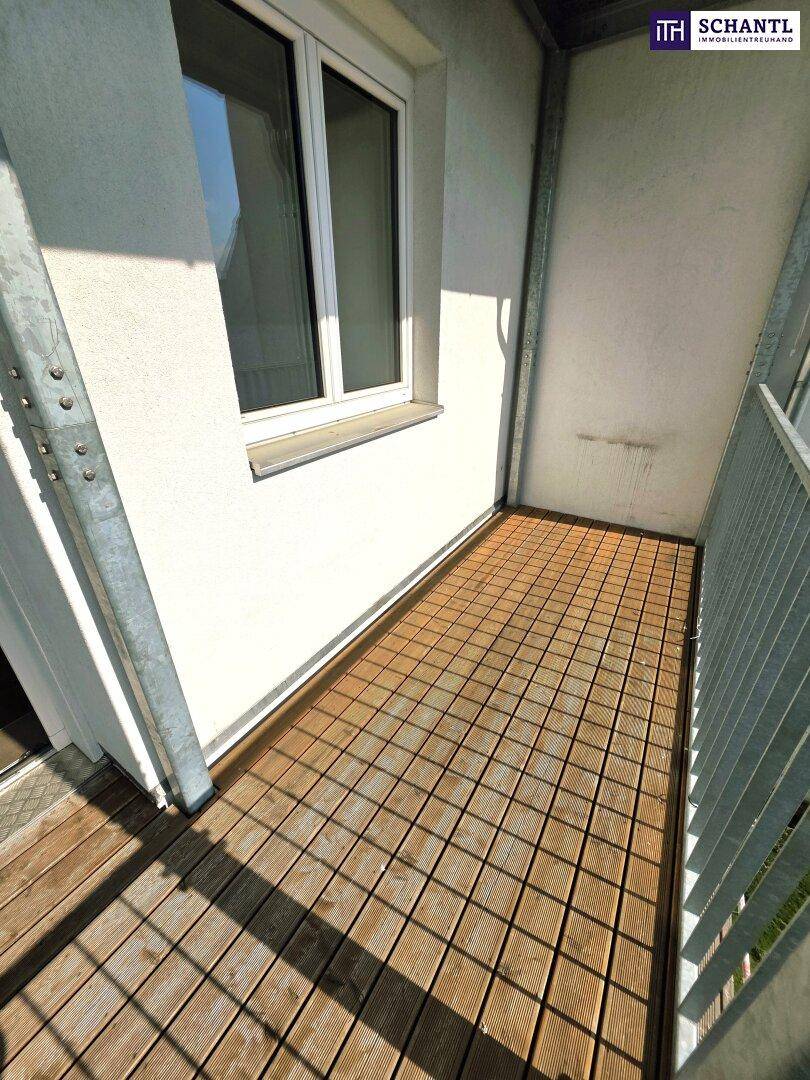 Kleiner Balkon mit Holzdielen und Fenster, bietet einen privaten Außenbereich.