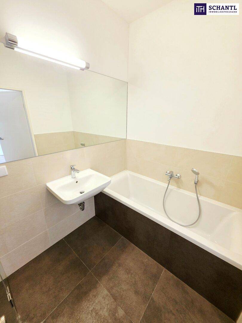 Helles Badezimmer mit Badewanne, Waschbecken und großem Wandspiegel.