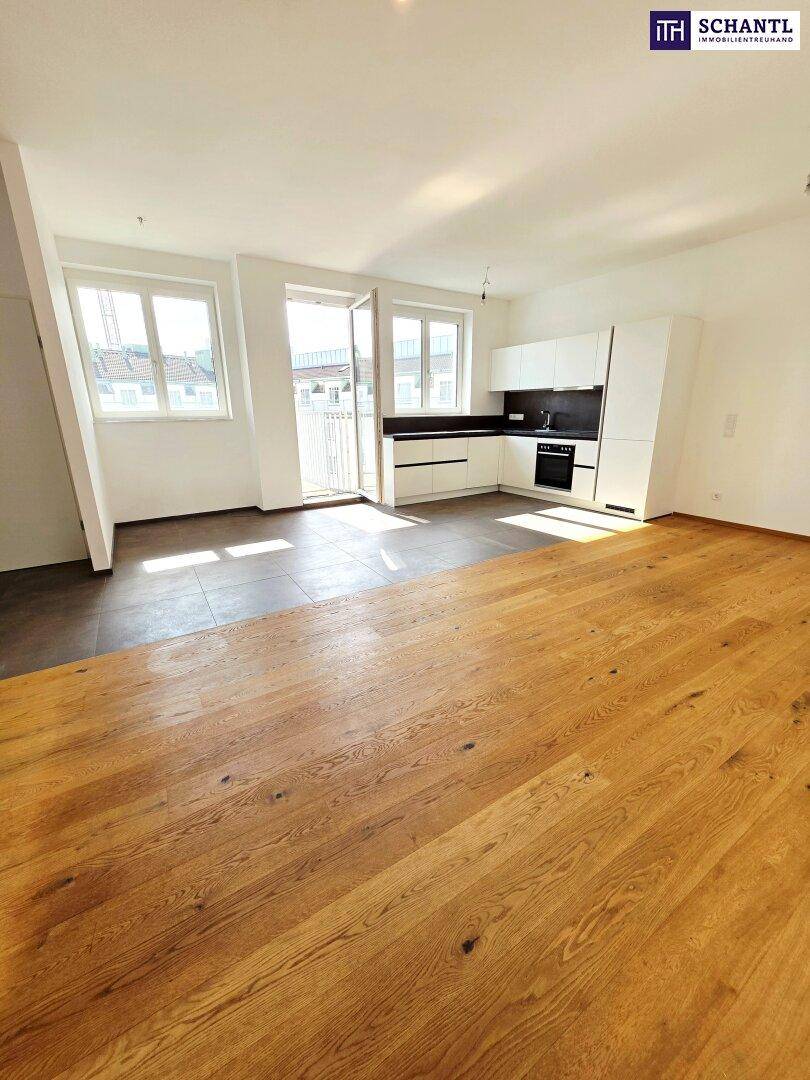 Heller offener Wohnbereich mit moderner Küchenzeile, Holzboden und Balkonzugang.