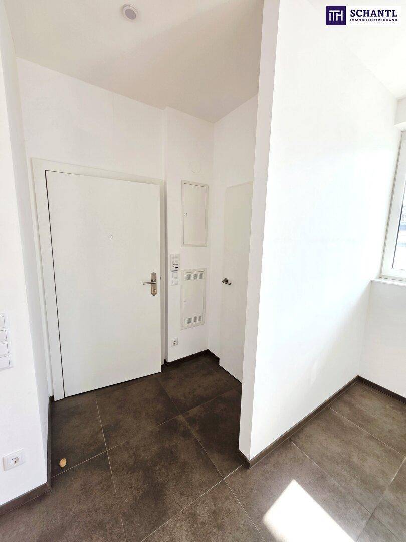 Eingangsbereich mit Fliesenboden und weißen Wänden, führt zu weiteren Räumen.