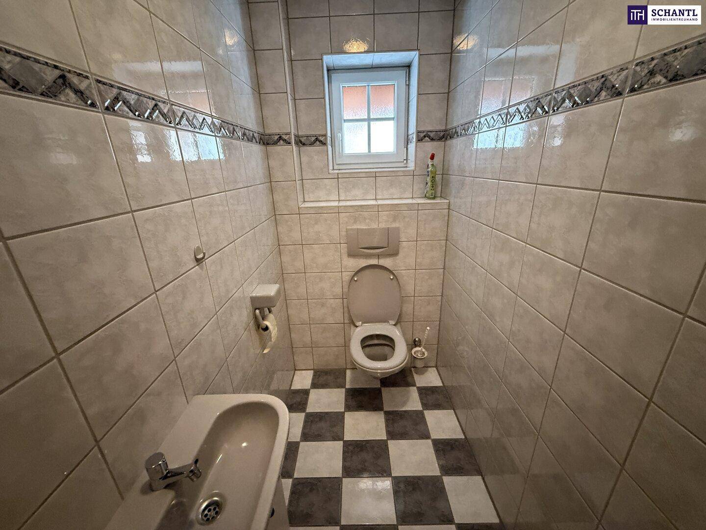 Gäste-WC mit Bidet, wandhängendem WC und markantem schwarz-weißem Fliesenboden.