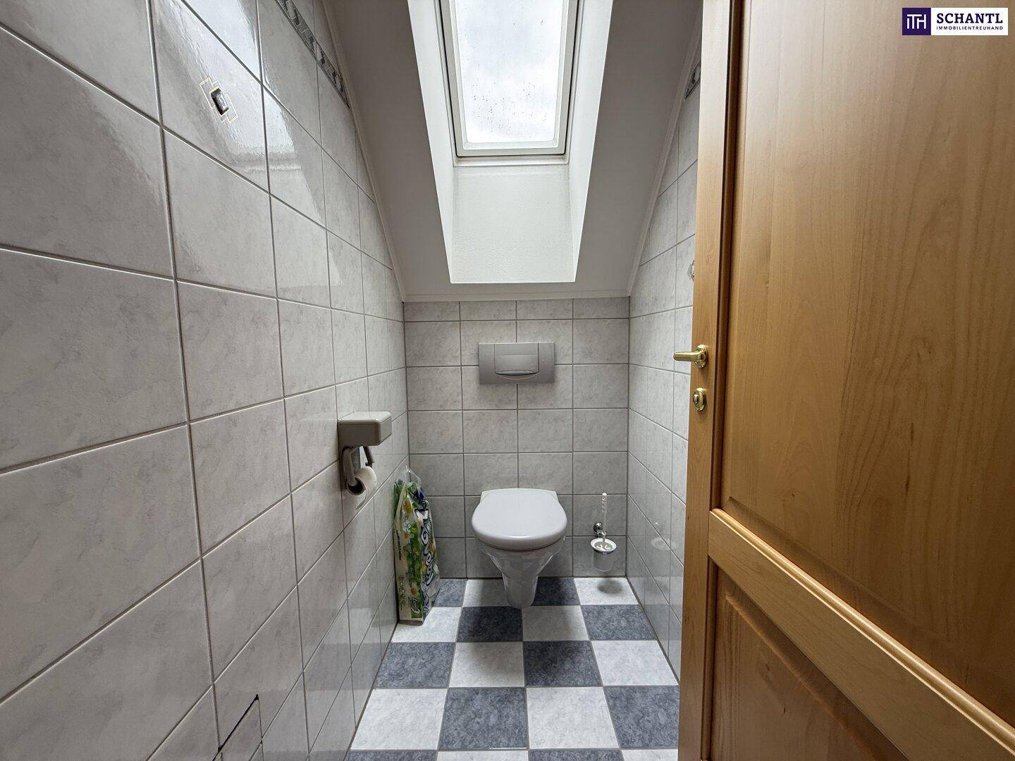 Separates WC im Dachgeschoss mit Fliesenboden, wandhängendem WC und Dachfenster für Tageslicht.