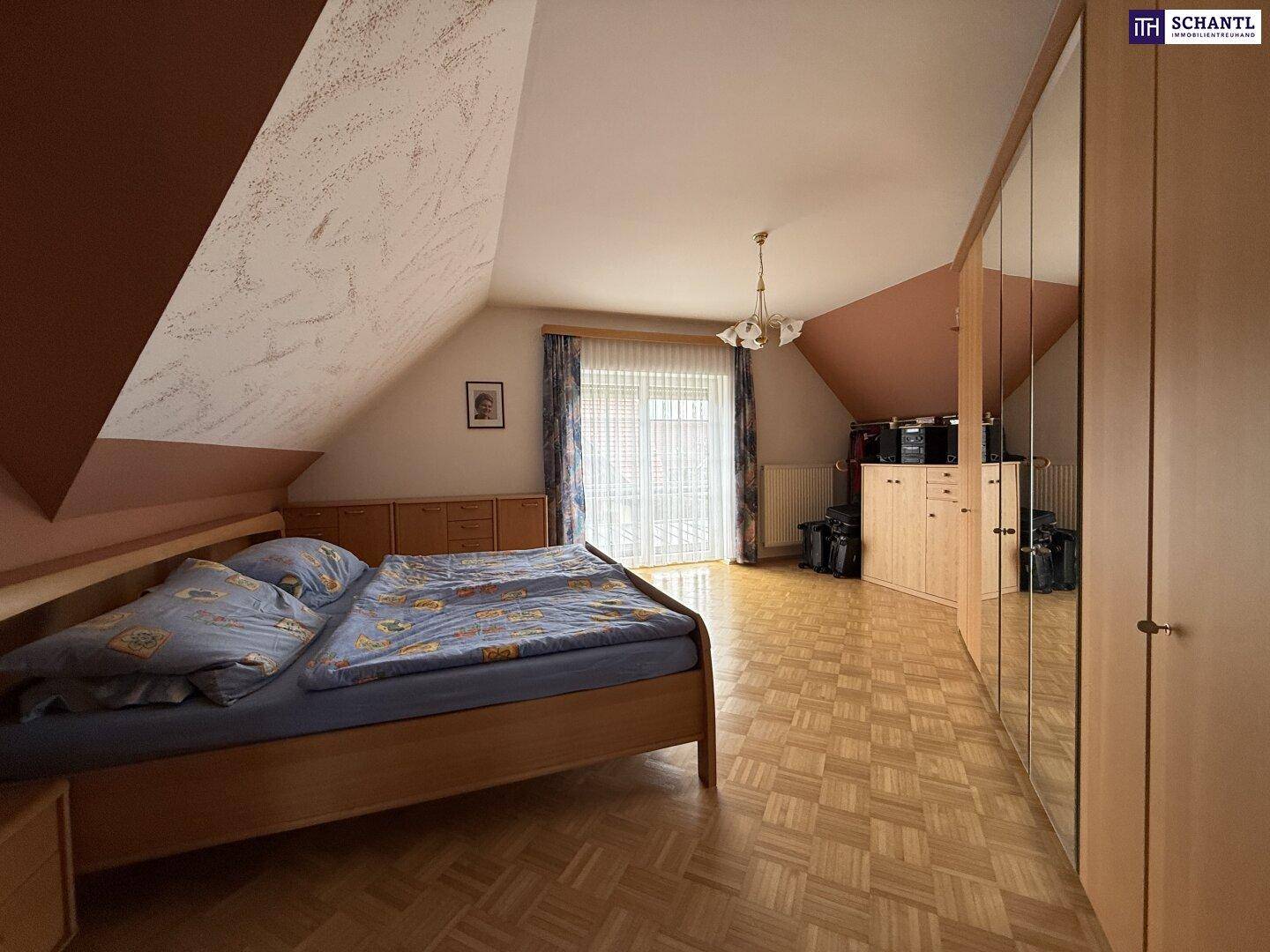 Schlafzimmer im Dachgeschoss mit Doppelbett, Spiegelschrank und Zugang zu einem kleinen Balkon.