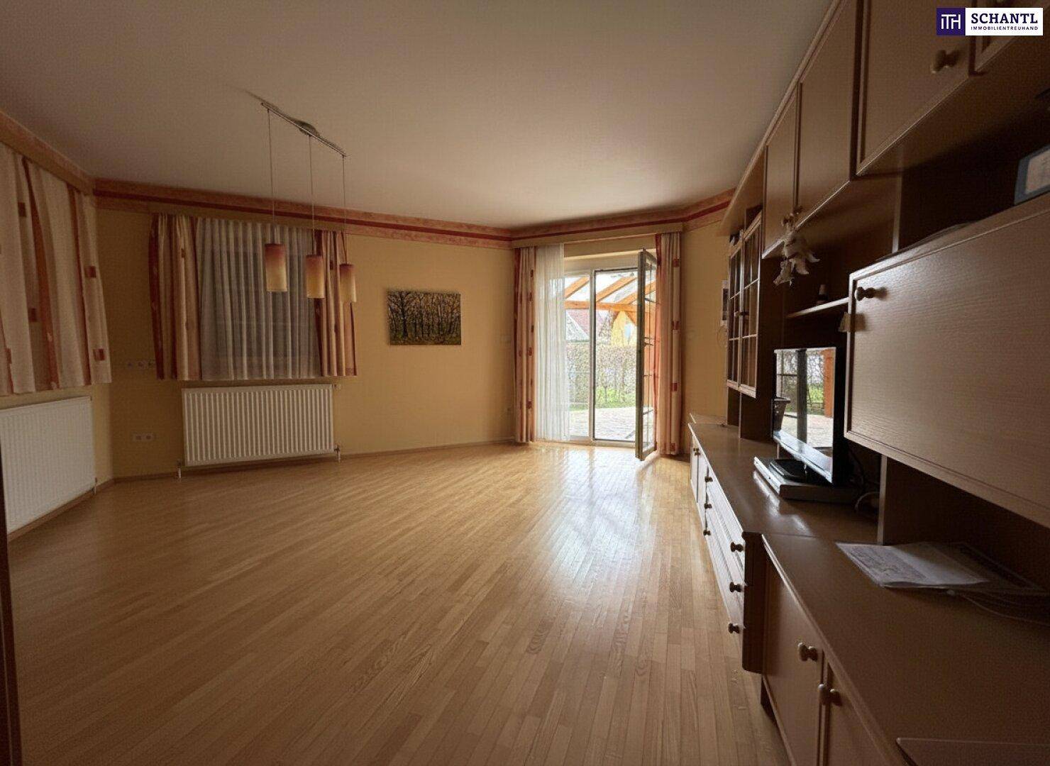 Helles Wohnzimmer mit Parkettboden, großem Fenster und direktem Zugang zur Terrasse.
