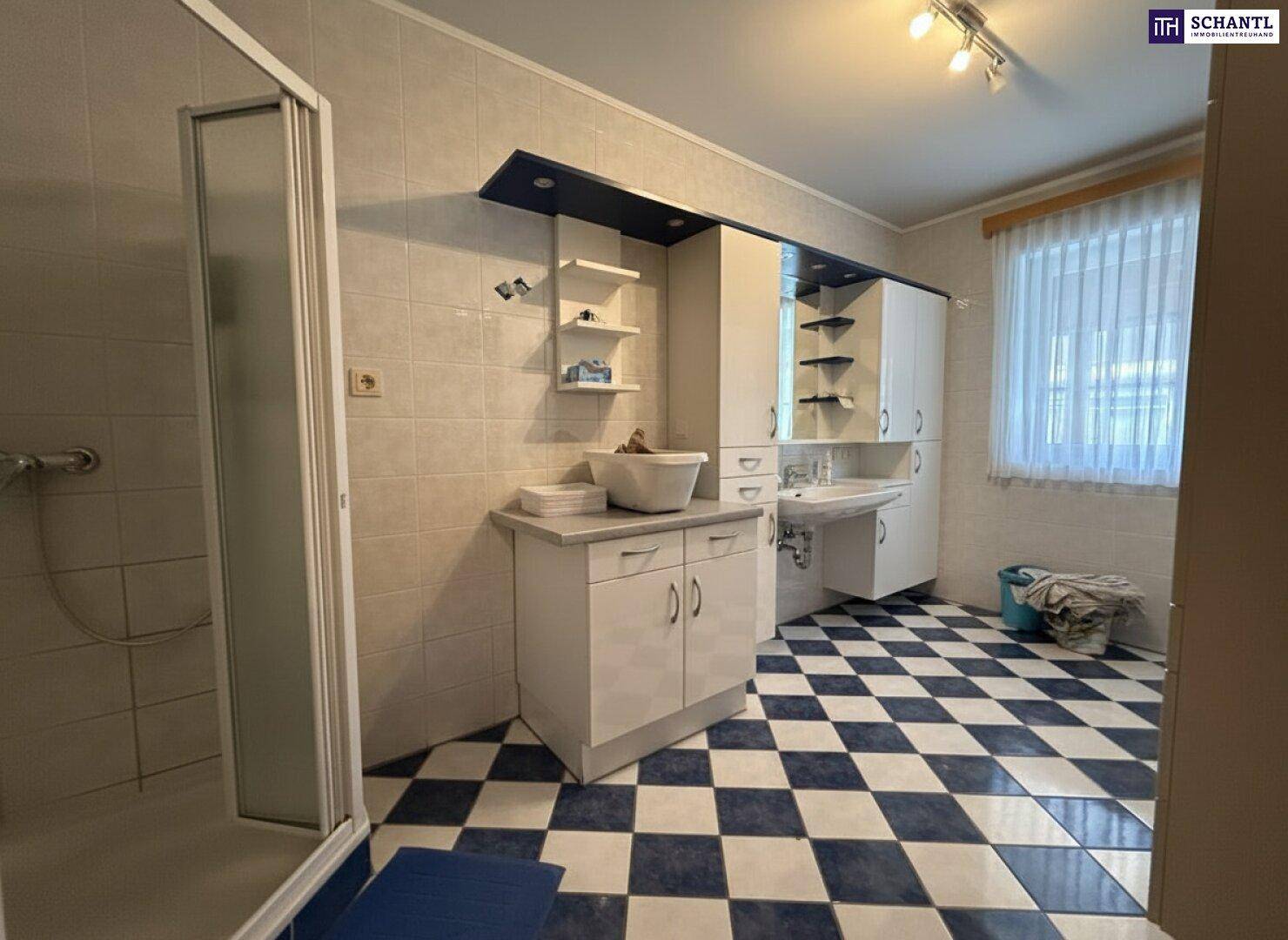 Geräumiges Badezimmer mit Duschkabine, Waschtisch und auffälligem blau-weißem Fliesenboden.