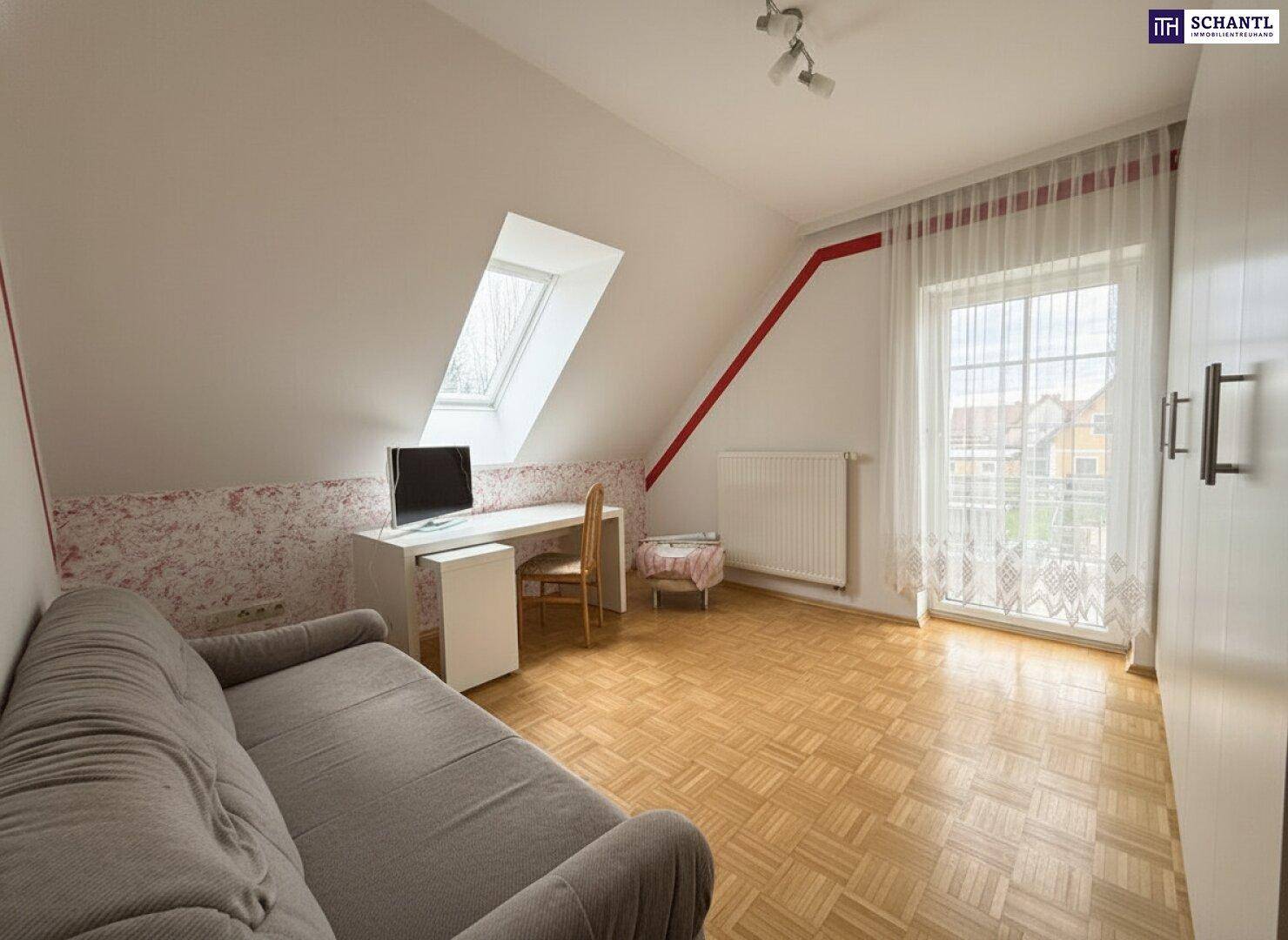 Zimmer im Dachgeschoss mit Schlafsofa, Schreibtisch und Zugang zu einem französischen Balkon.