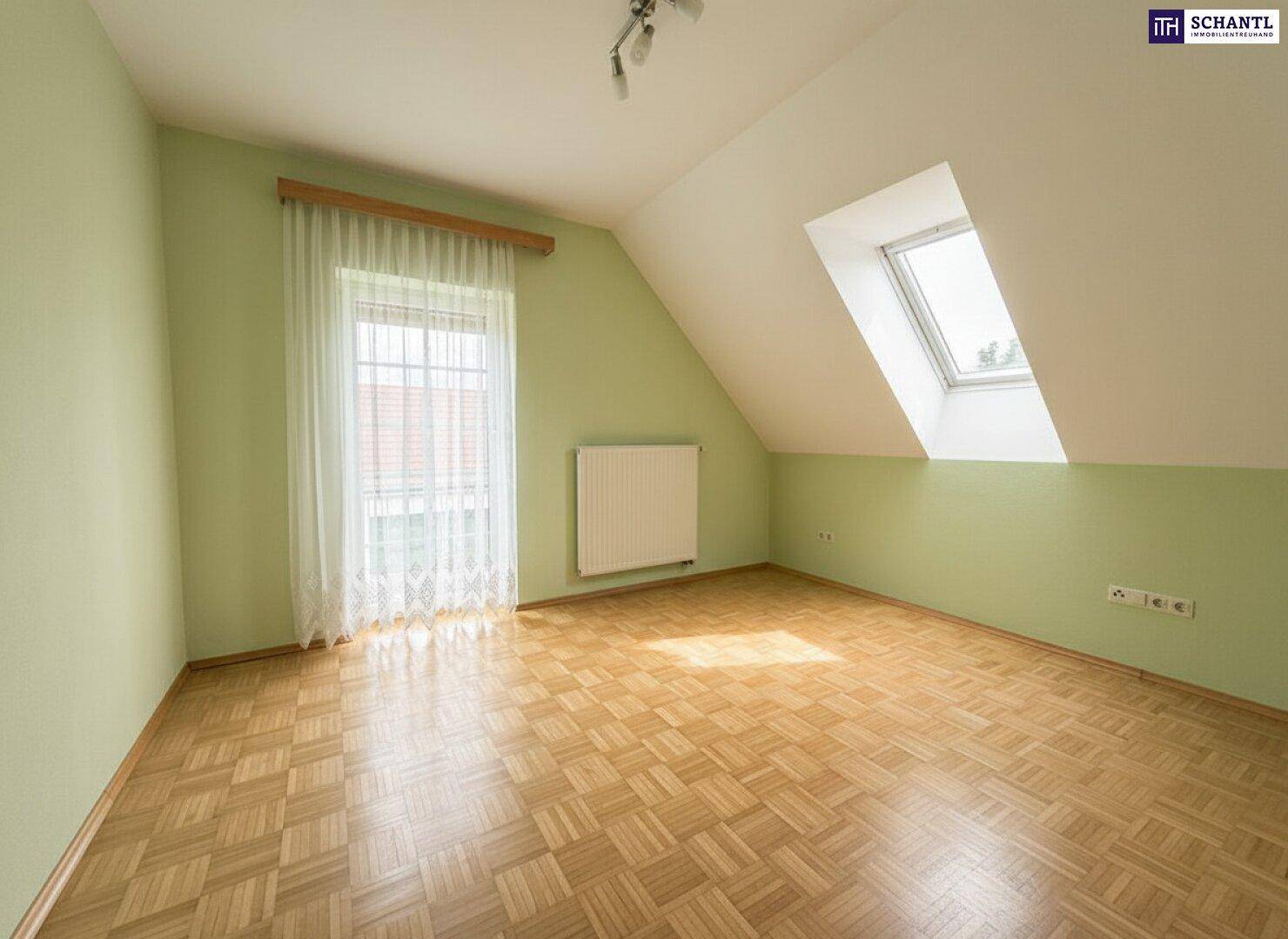 Helles Zimmer im Dachgeschoss mit Parkettboden, Dachfenster und freundlichen grünen Wänden.