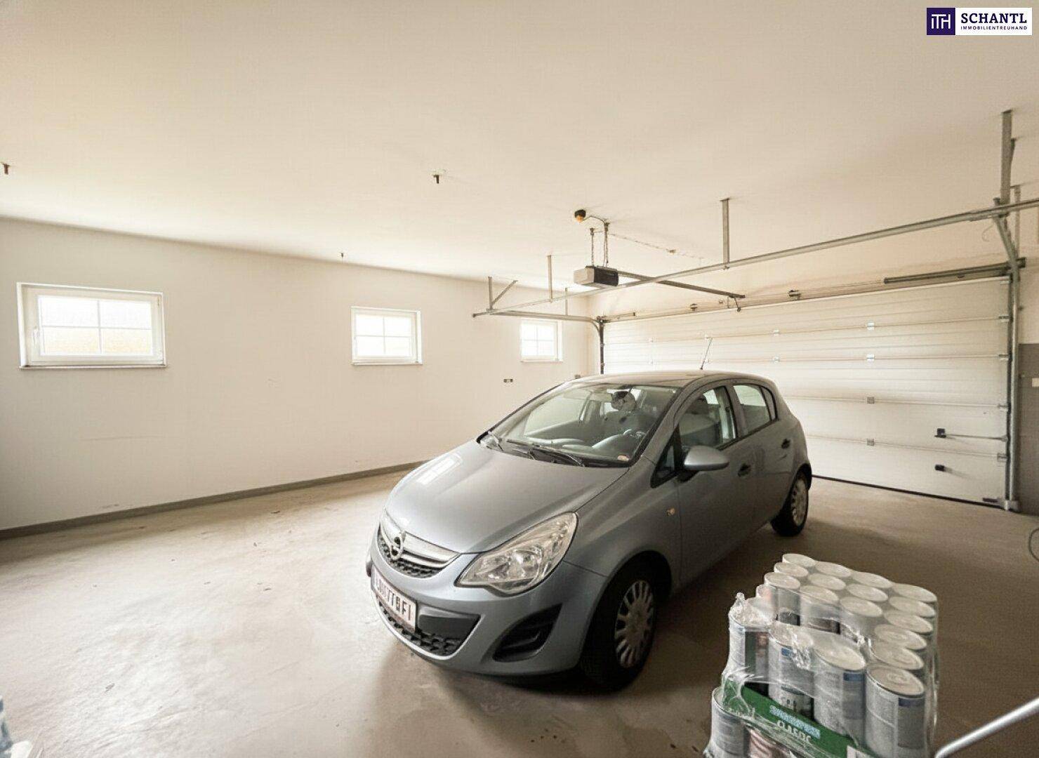 Geräumige Garage mit einem geparkten Auto, Fenstern und ausreichend Lagerfläche.