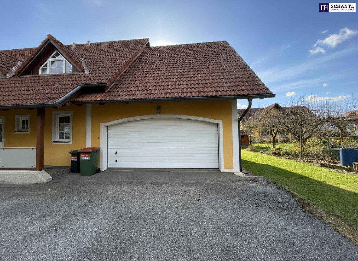 Garageneinfahrt mit automatischem Tor und Mülltonnen, seitlich am Haus gelegen.