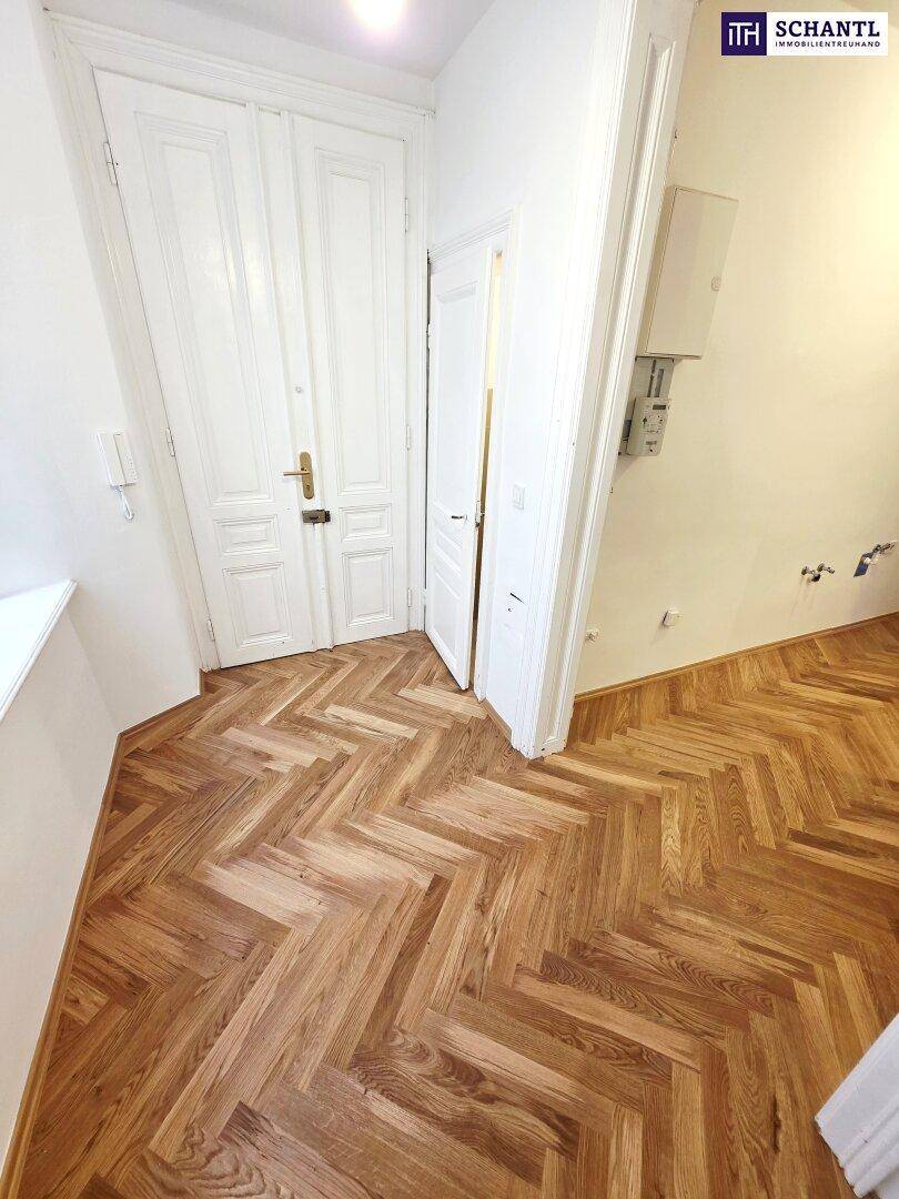 Eingangsbereich mit Fischgrätparkett und klassischer Doppeltür, die in die Wohnung führt.
