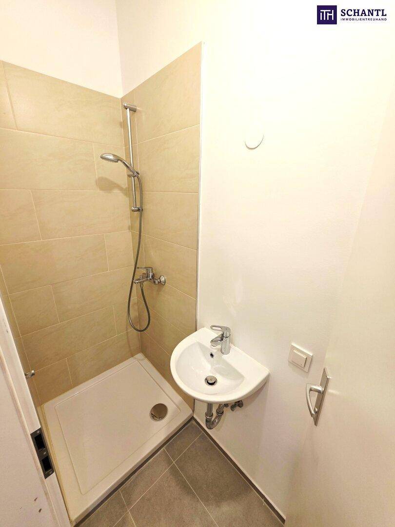 Kleines Badezimmer mit Dusche, Waschbecken und beigefarbenen Fliesen, funktional und hell.