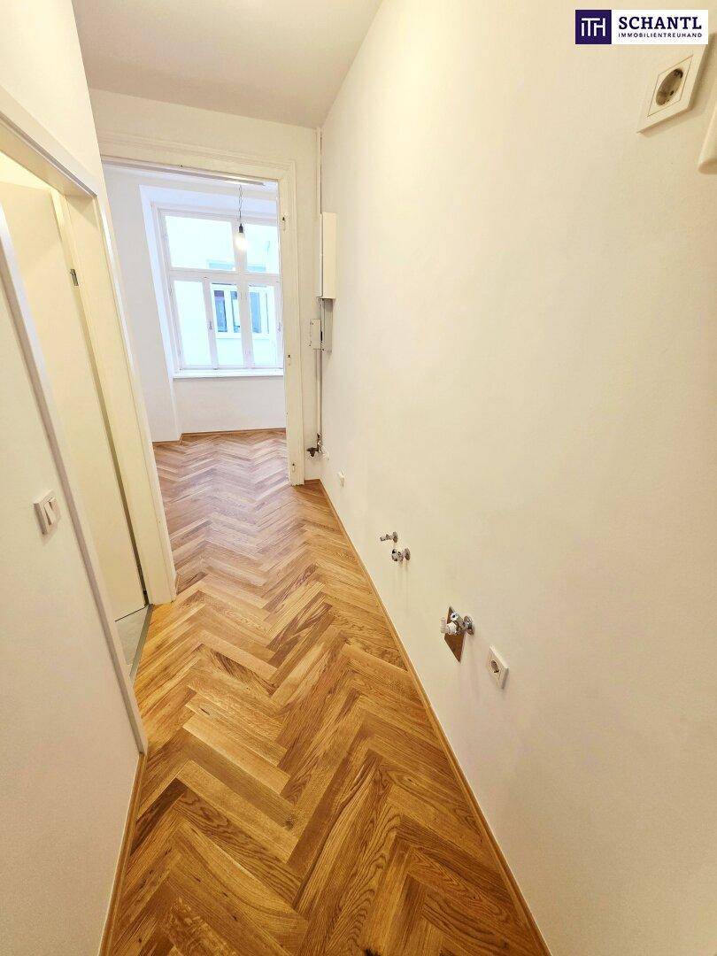 Langer Flur mit Fischgrätparkett und Anschlüssen für Wasser und Strom an der Wand.
