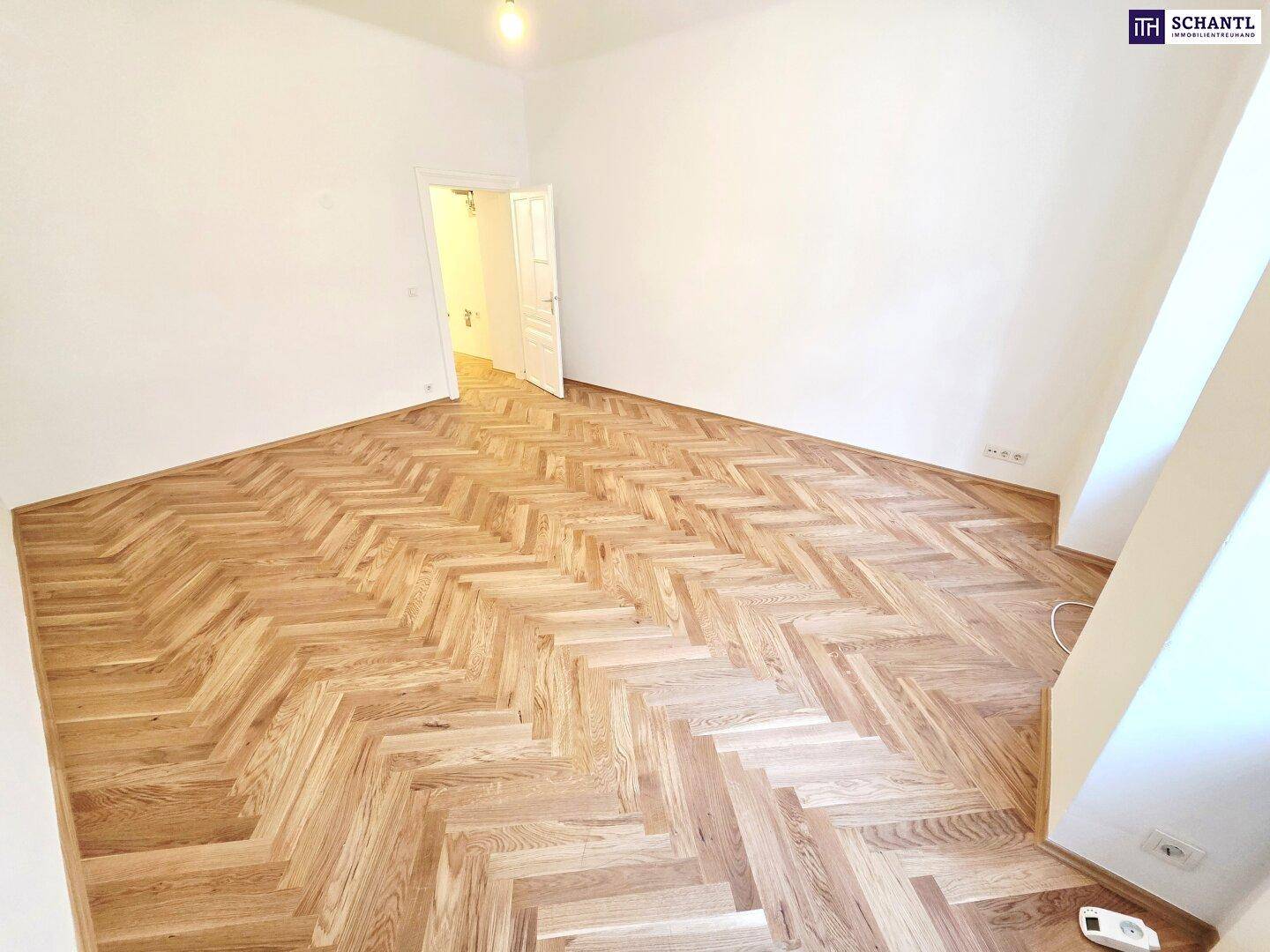 Geräumiges Zimmer mit Fischgrätparkett und weiß gestrichenen Wänden, ideal für individuelle Gestaltung.