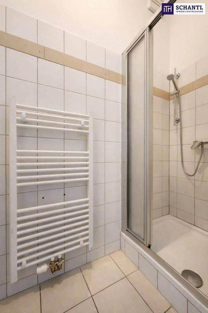 Modernes Badezimmer mit weißen Fliesen, einer Duschkabine und einem praktischen Handtuchheizkörper.