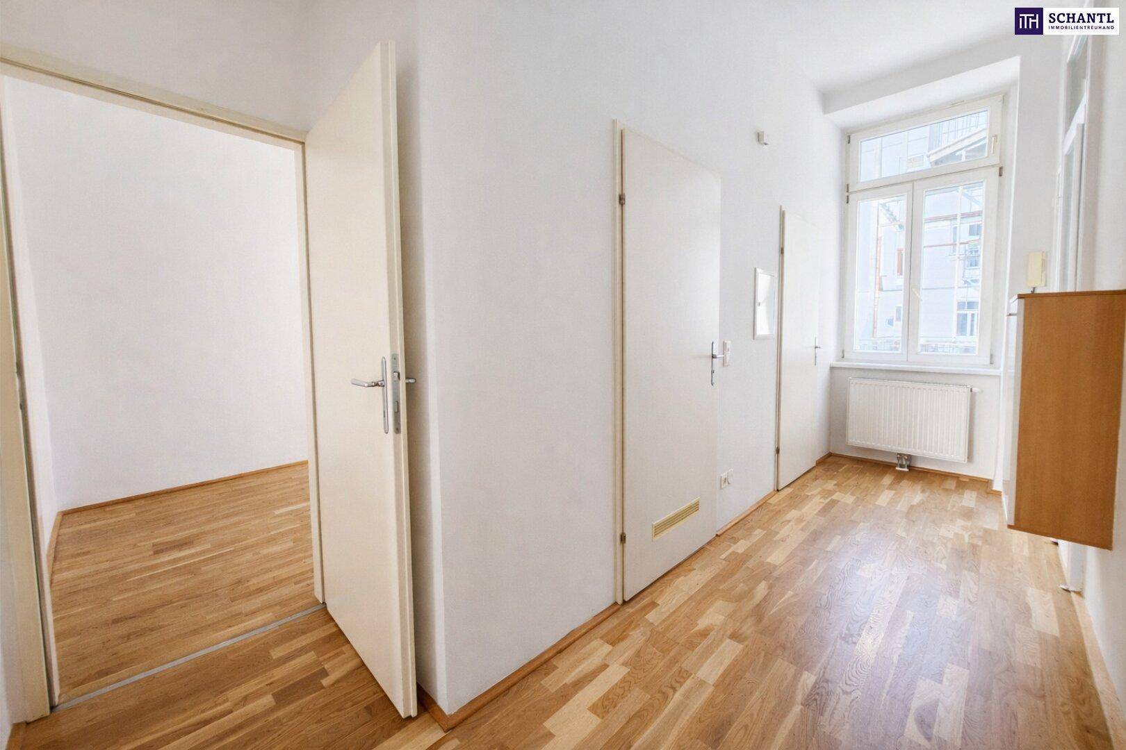 Geräumiger Flur mit Parkettboden, mehreren Türen und einem Fenster am Ende des Ganges.