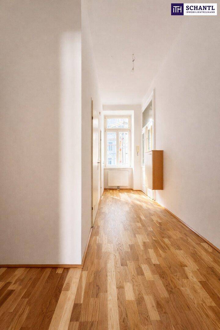 Heller Flur mit Parkettboden, der zu einem Fenster am Ende führt und viel Licht hereinlässt.