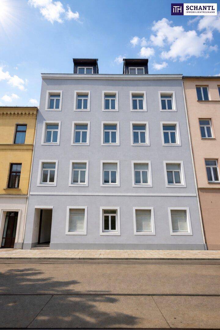 Mehrstöckiges Wohngebäude mit frisch renovierter hellgrauer Fassade und vielen Fenstern unter blauem Himmel.