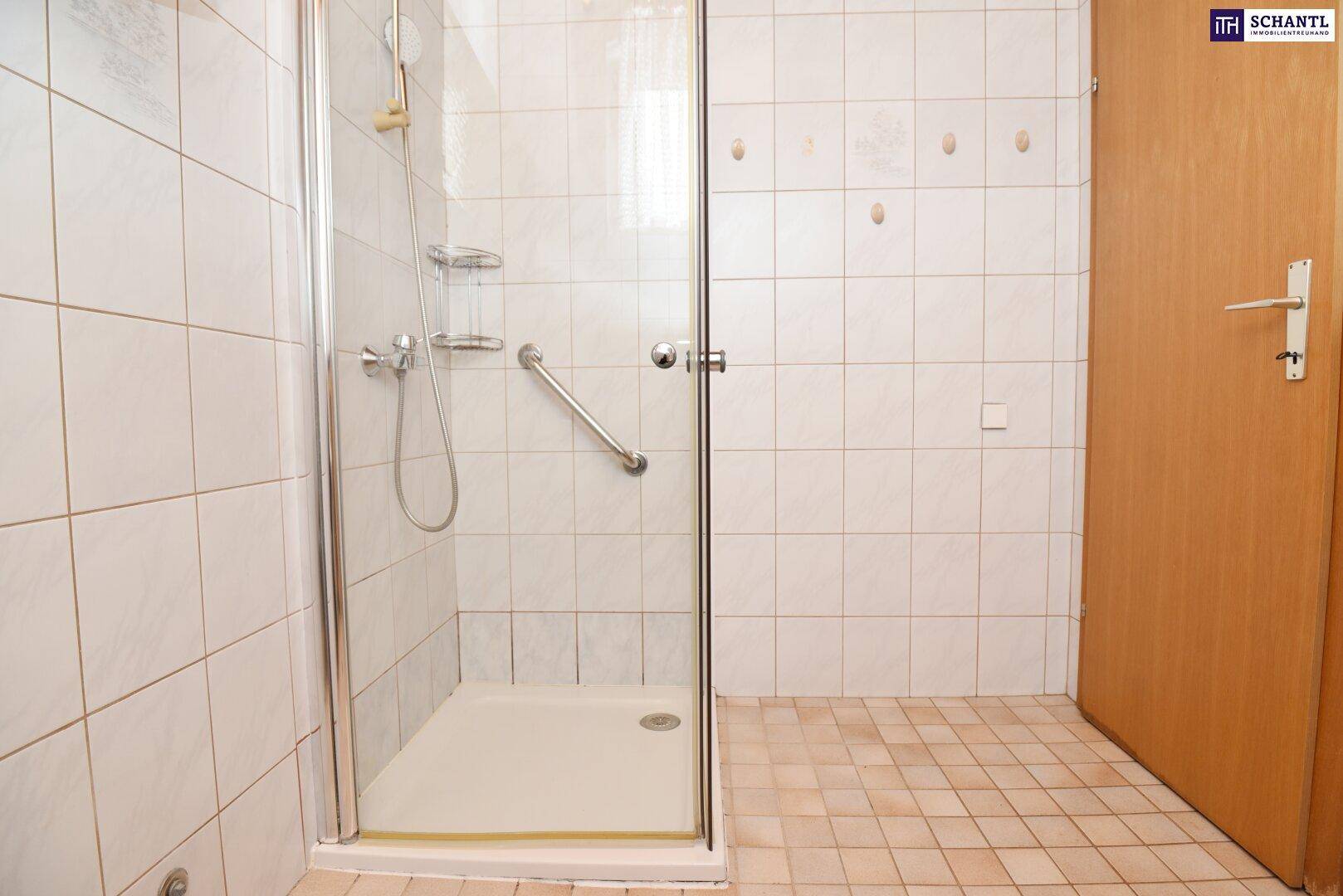 Badezimmer mit Duschkabine, weißen Fliesen und Haltegriff.