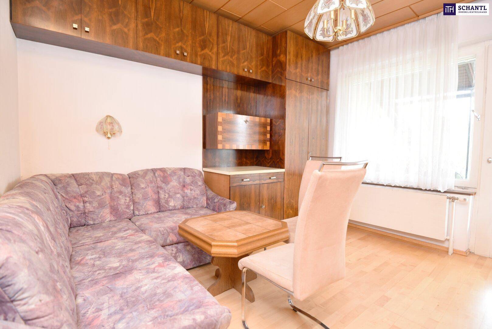 Gemütliches Wohnzimmer mit Holzdecke, floralem Sofa und Einbauschränken.
