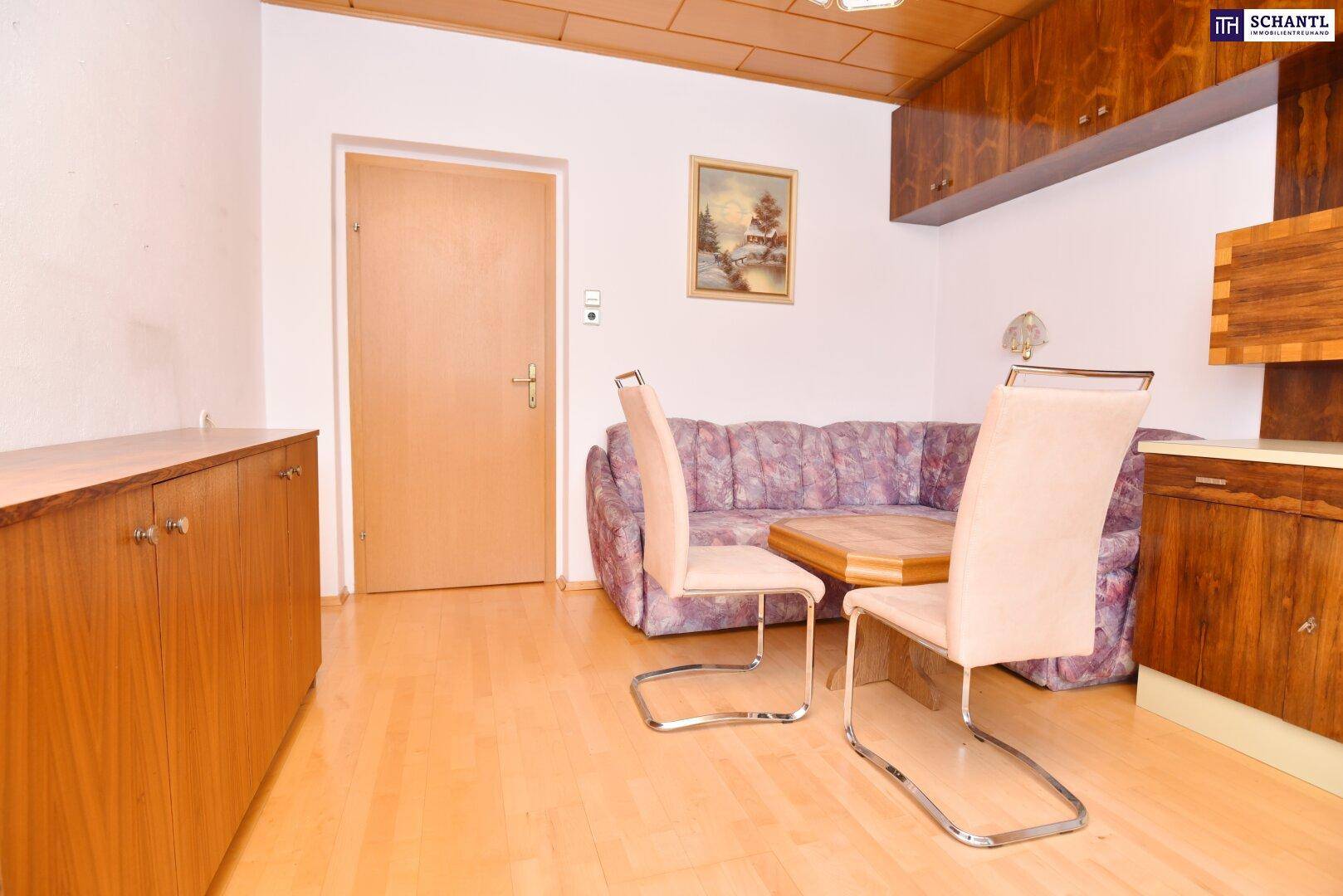 Wohnzimmer mit Holzdecke, floralem Sofa und Einbauschränken, Blick zur Tür.