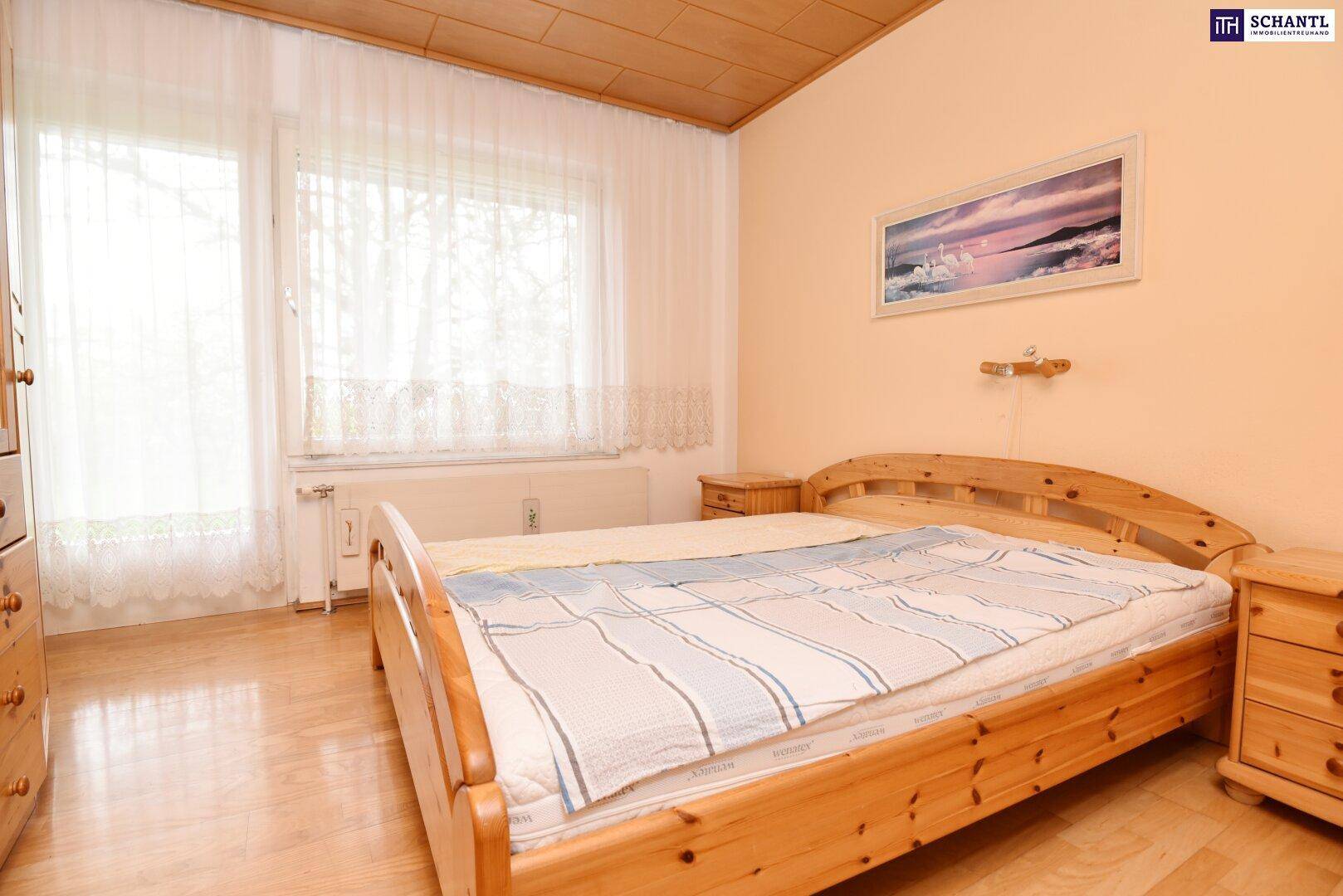 Schlafzimmer mit hellem Holzbett, Holzdecke und Fenster mit viel Tageslicht.