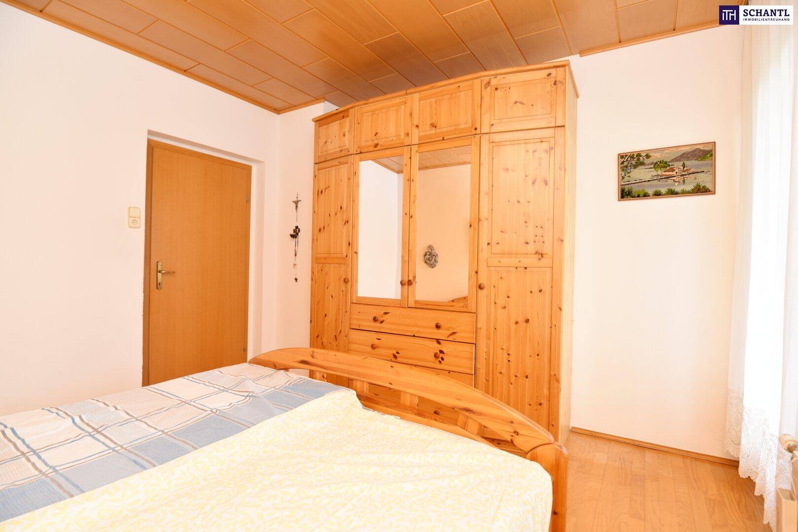 Schlafzimmer mit großem Holzschrank, Spiegel und Holzbett.
