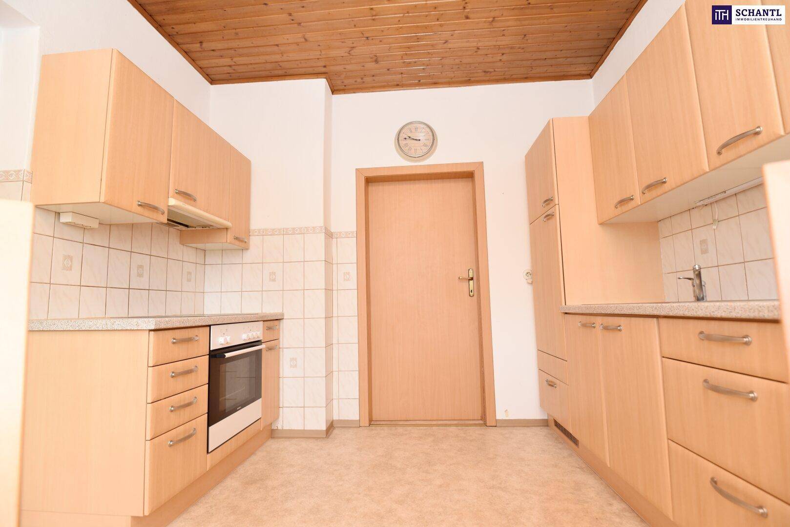 Küche mit Holzschränken, Fliesenrückwand und Blick zur Zimmertür.